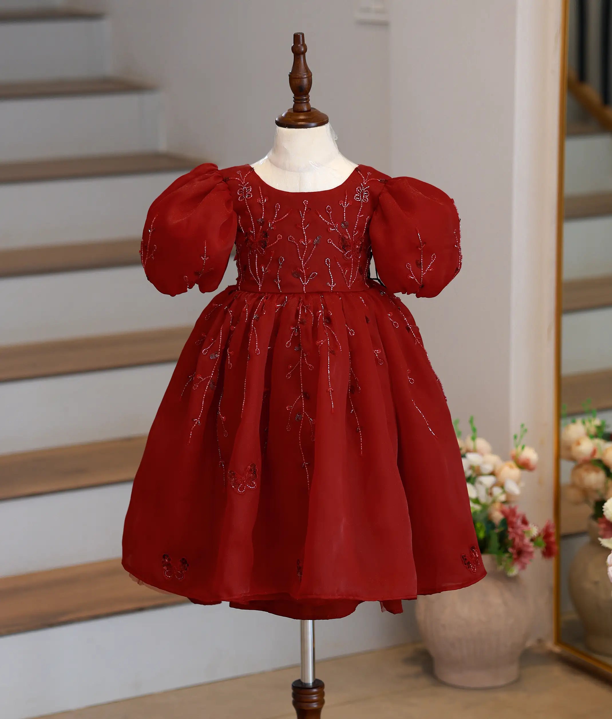 Front view of a maroon plain organza gown for baby girls with butterfly handwork and puffed sleeves