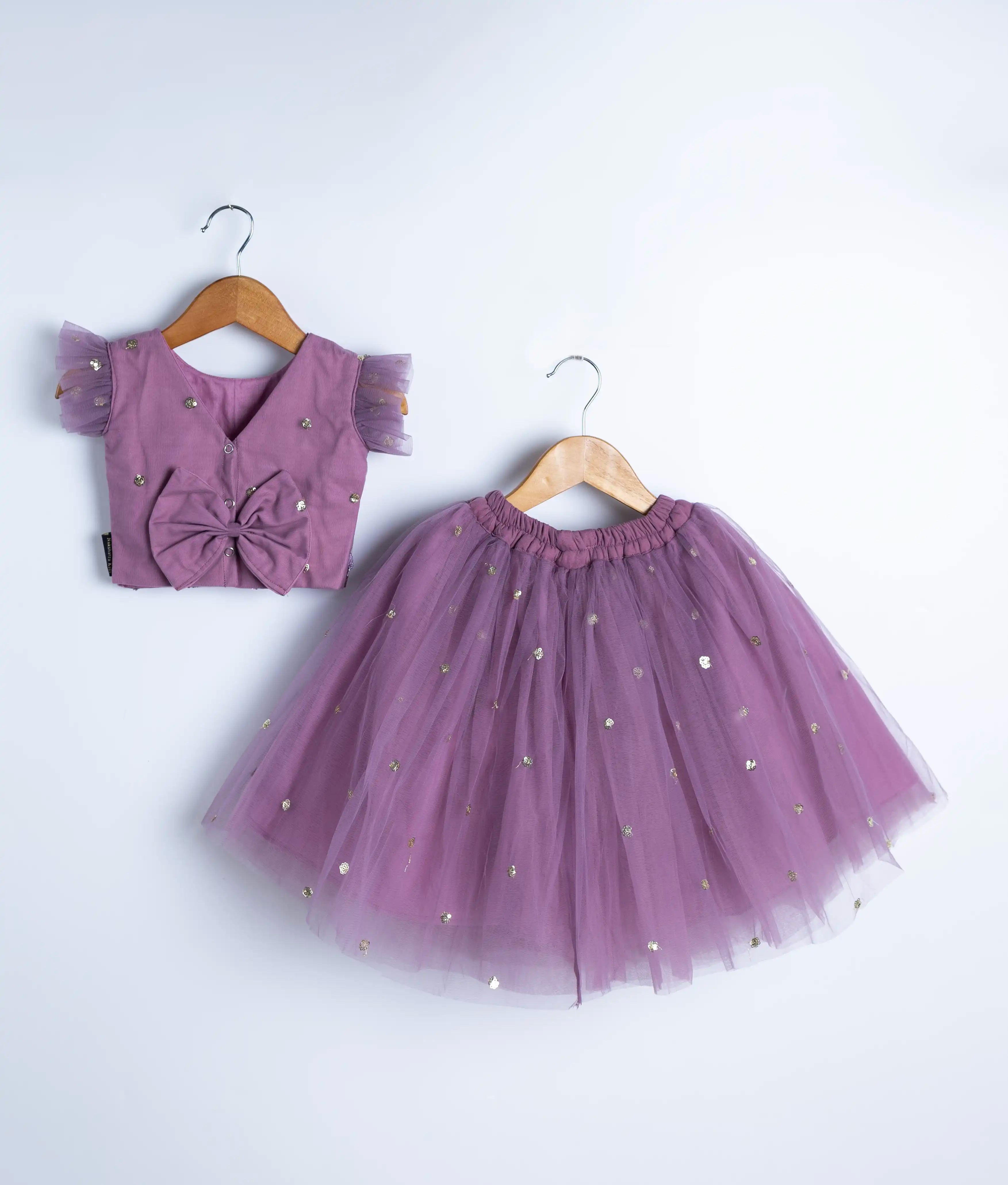 Flat lay of handmade mauve baby girl skirt and top with pearl and floral applique