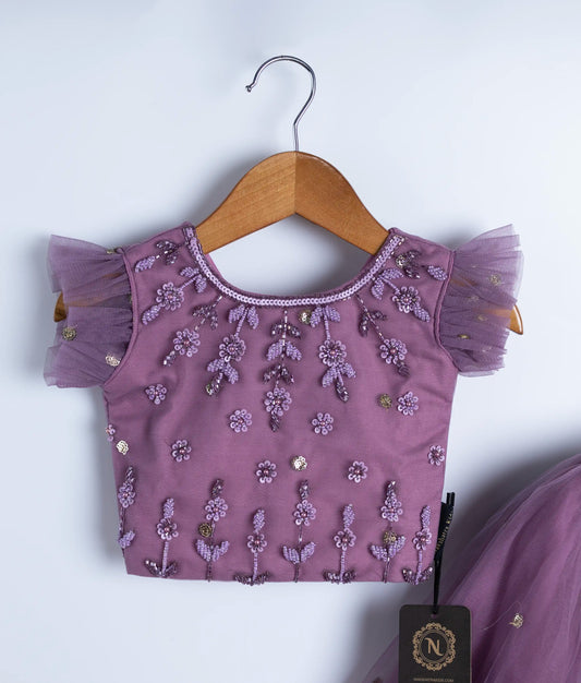 Close-up of mauve baby girl top with handmade floral embroidery and flutter sleeves