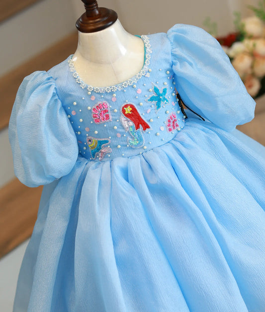 Close-up of the mermaid theme handwork featuring starfish and shells on the bodice of the pastel blue frock