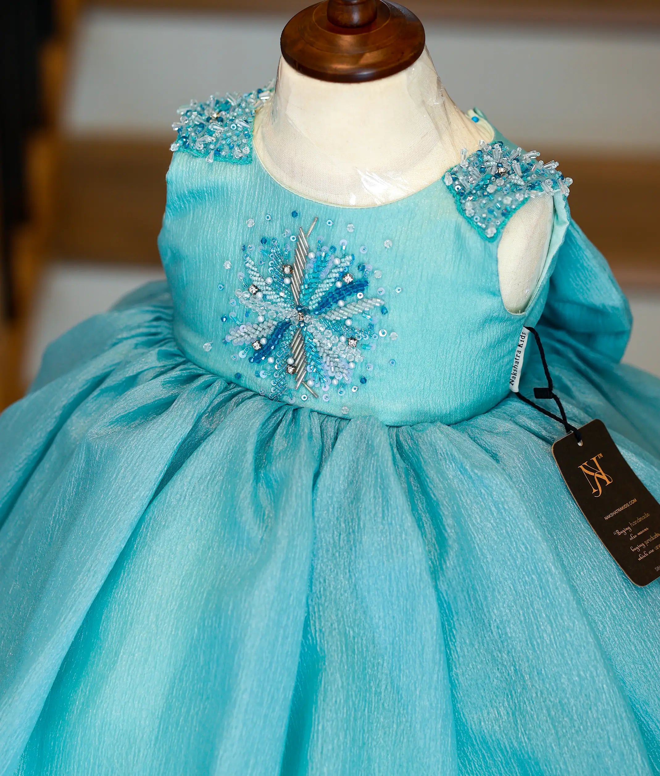 Back view of the Munsell blue organza frock featuring a round neckline, show button, and a decorative bow
