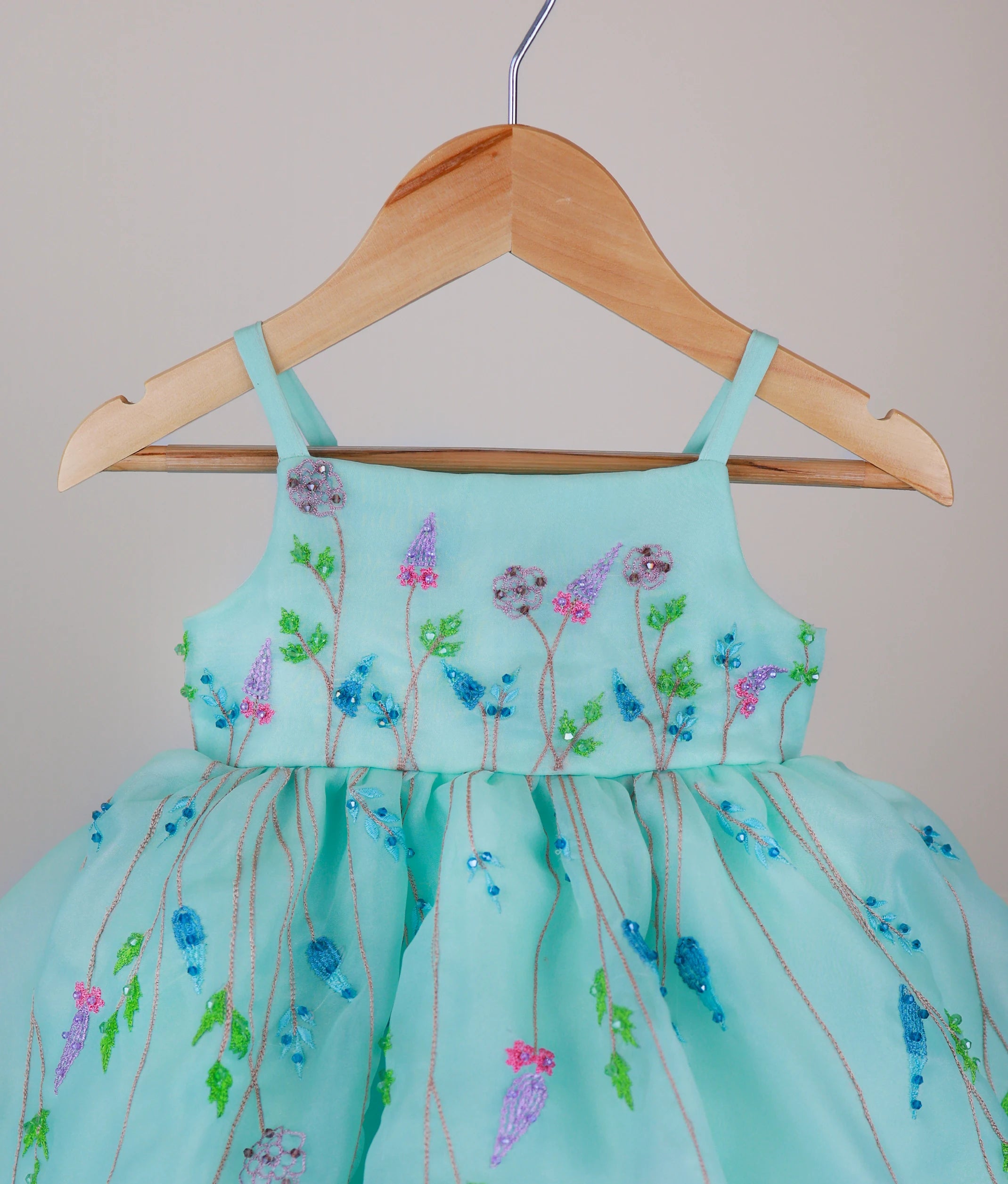 Close-up of the ocean green dress bodice showing the shoulder straps and detailed pastel floral embroidery