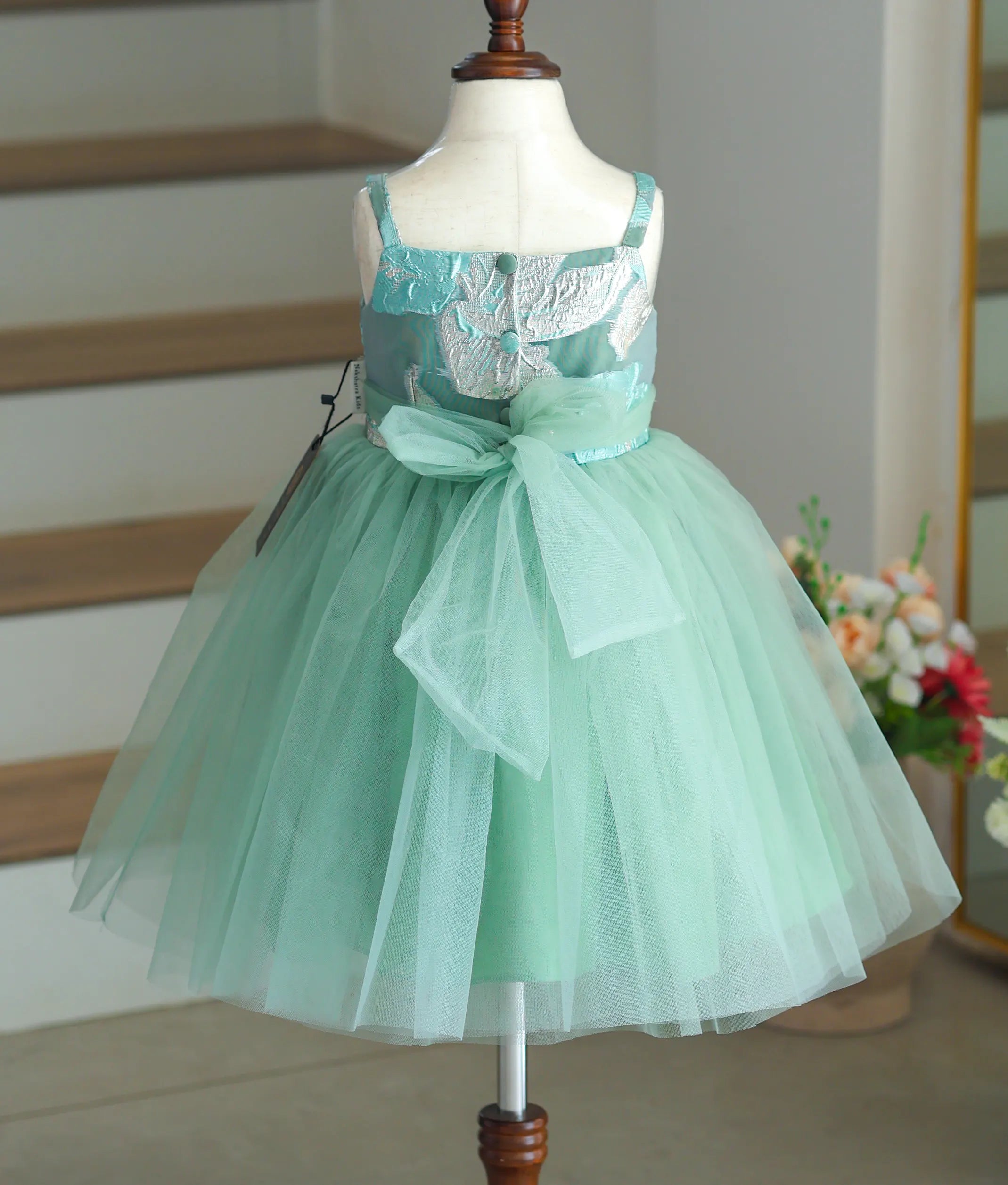Back view of the frock showing the show buttons, tie-back, and ocean green net bottom.