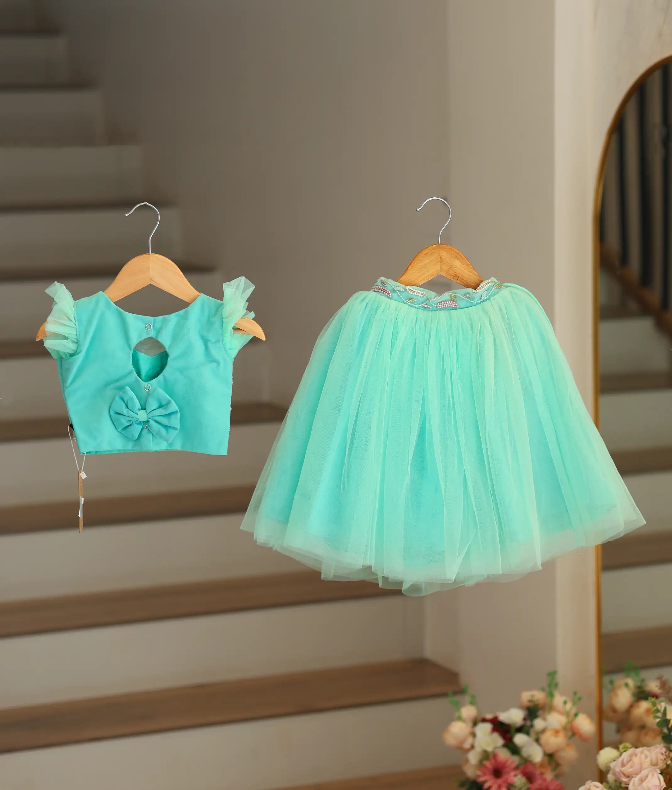 Back view of the ocean green top and skirt showing the keyhole opening, button, and decorative bow