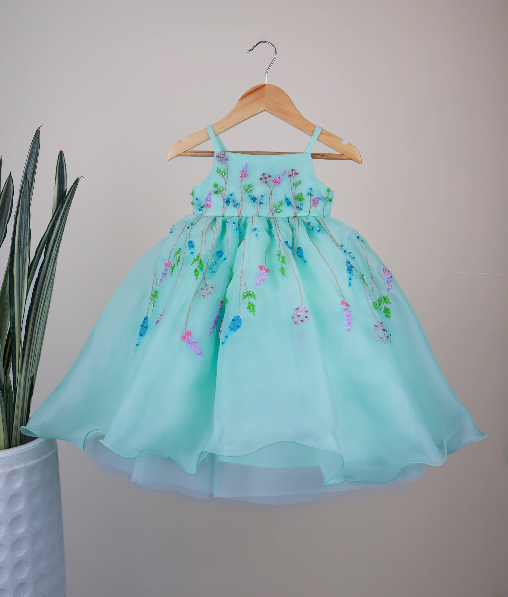 Front view of a pastel ocean green organza luxe gown for girls featuring intricate floral embroidery and a layered skirt