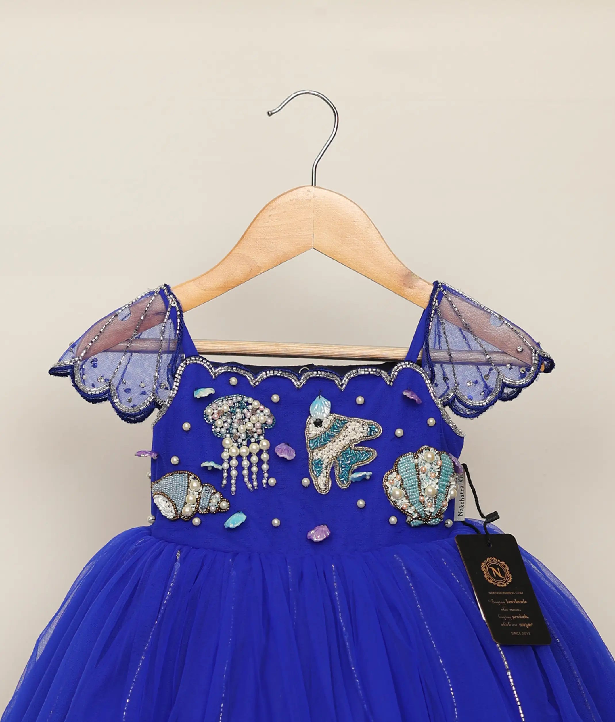 Close-up of the sea-themed handwork showing pearls, seahorse, and jellyfish designs on the royal blue bodice