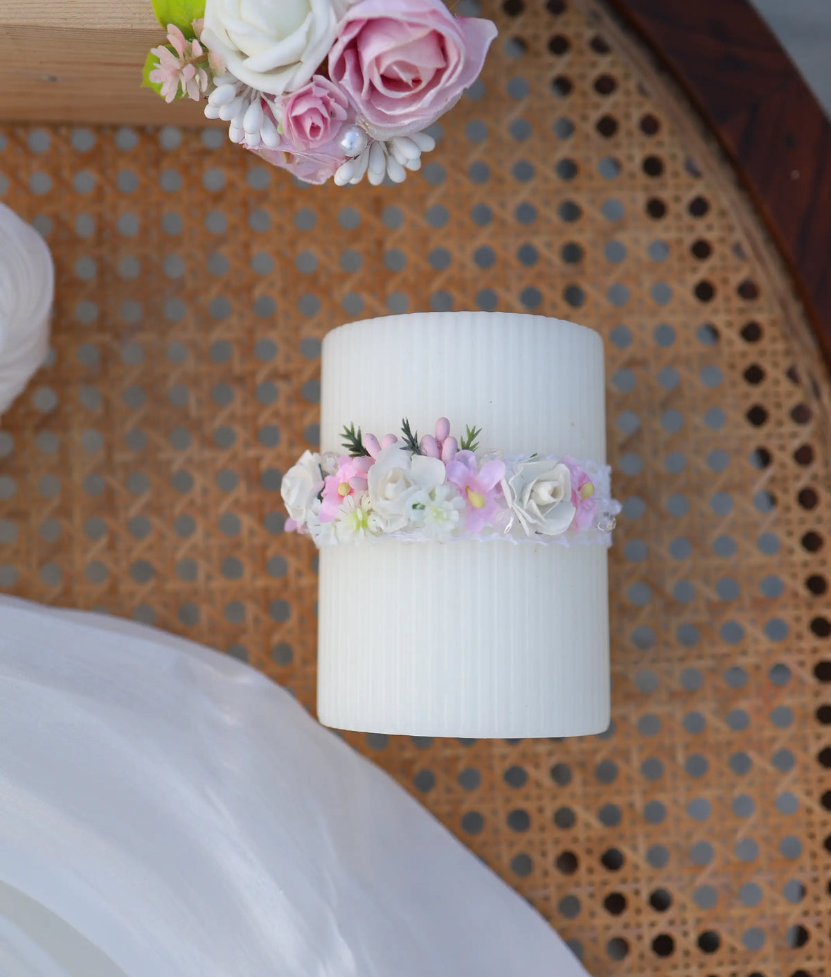 Ribbed off-white baptism pillar candle adorned with a handcrafted ring of pink and white flowers.
