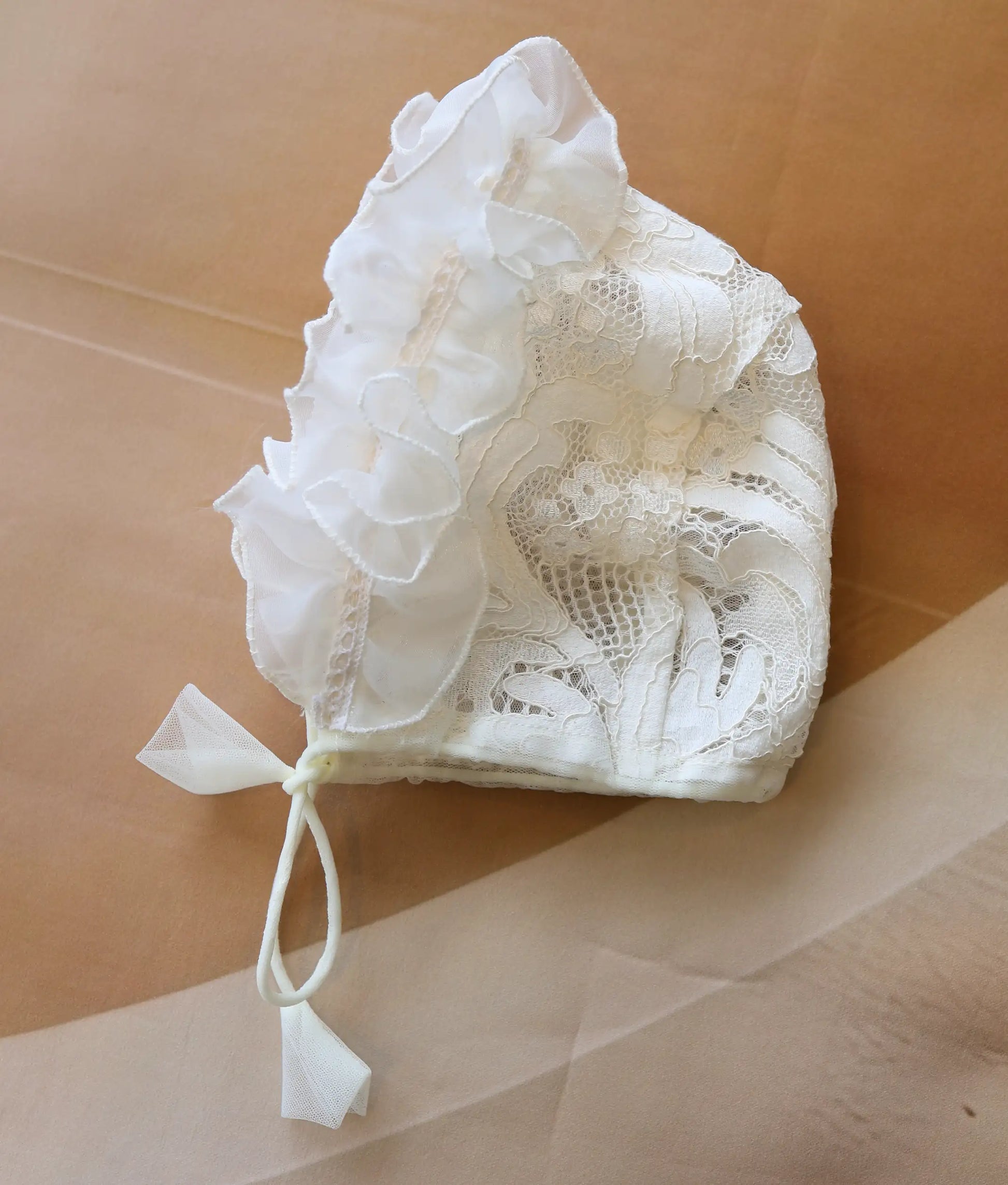 Close-up shot showing the intricate floral lace and ruffled design of the baptism cap.