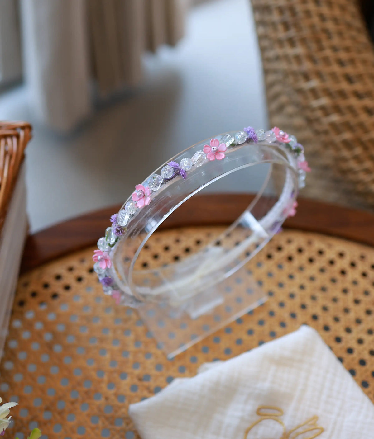 Delicate baby girl baptism headband styled with small pink flowers and crystal beads on a clear display stand.