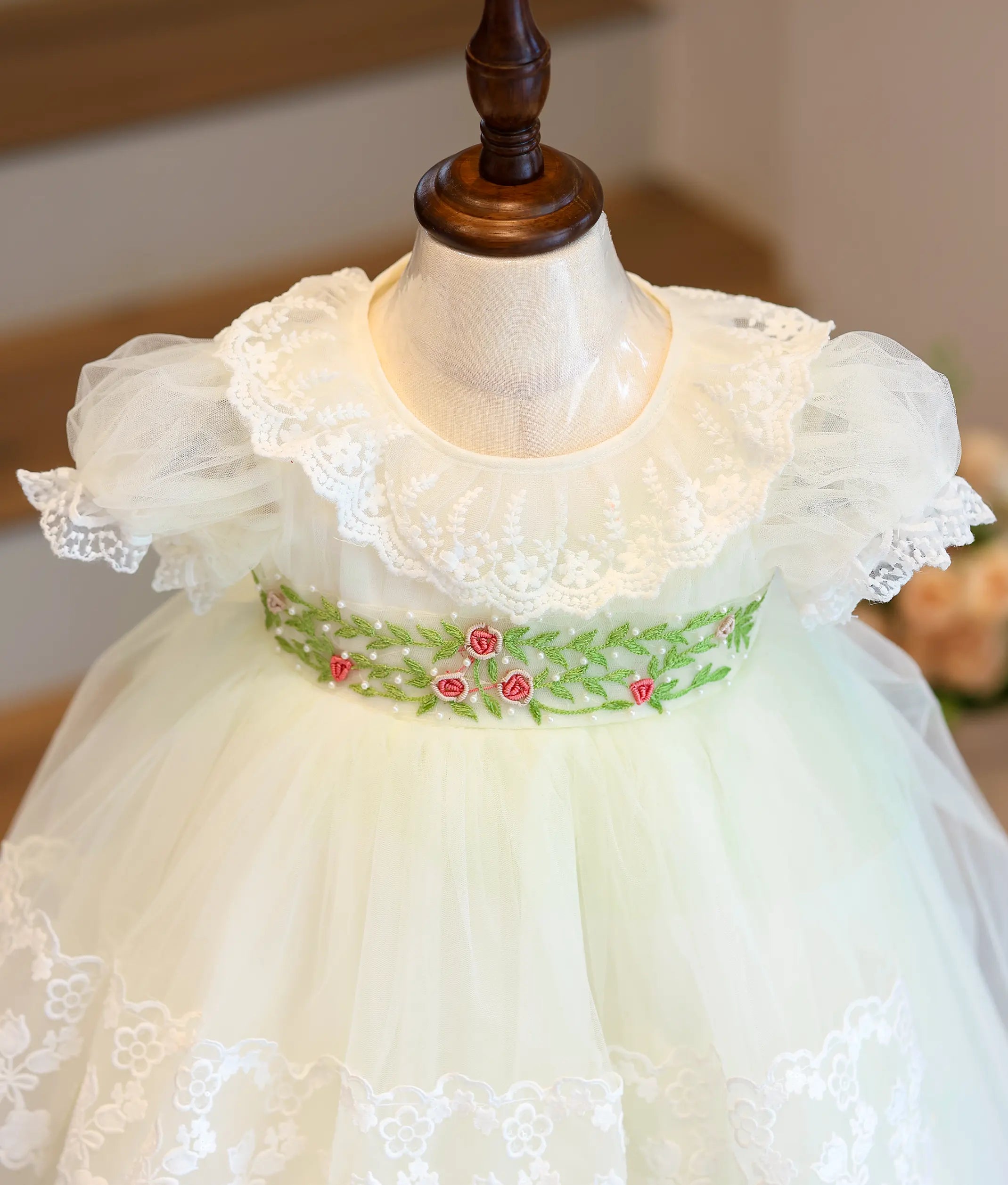 Close-up of off-white baptism dress featuring hand-embroidered floral waist detailing, lace collar and puff sleeves