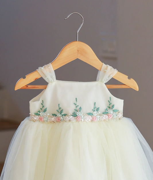 Close-up of the gathered tulle straps, floral handwork, and sequin belt detail on the baptism gown.