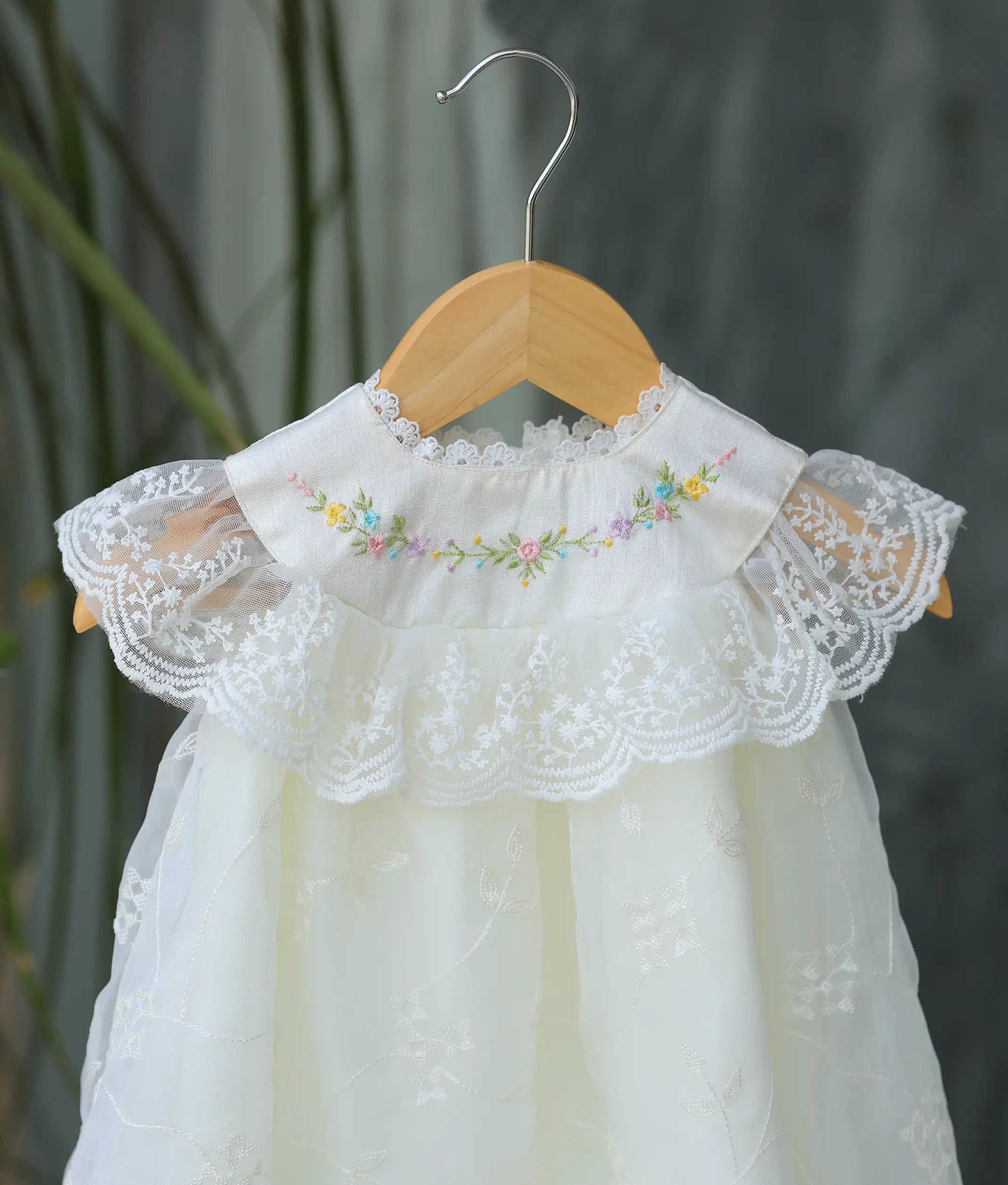 A close-up shot showing the short lace sleeves and the tiny colorful flowers on the collar of the off-white gown.