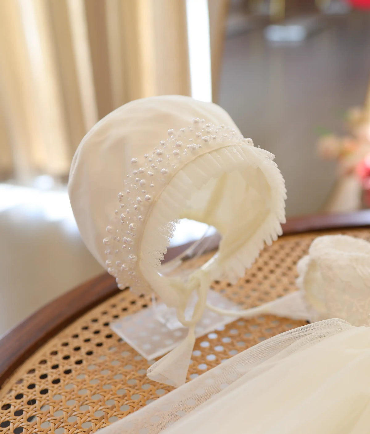 Off-white baby bonnet cap with delicate pearl work and frilled rim for christening outfit.
