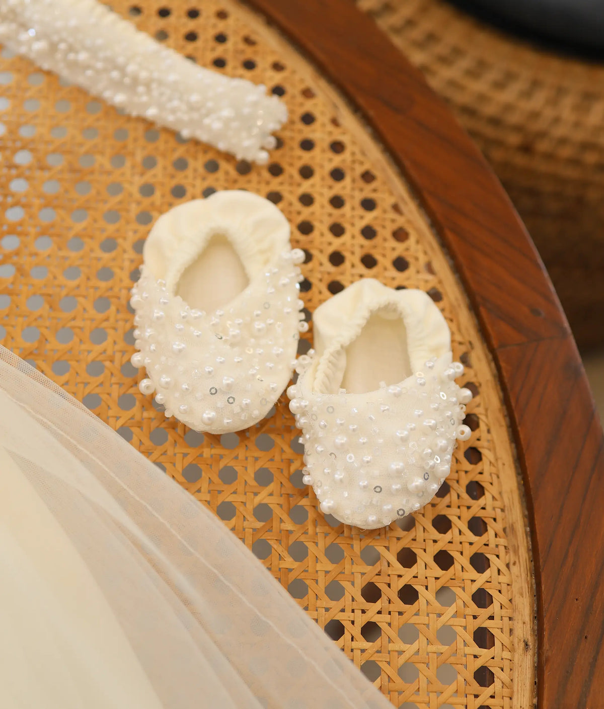 Close-up of off-white handworked pearl and sequin baby booties for christening.