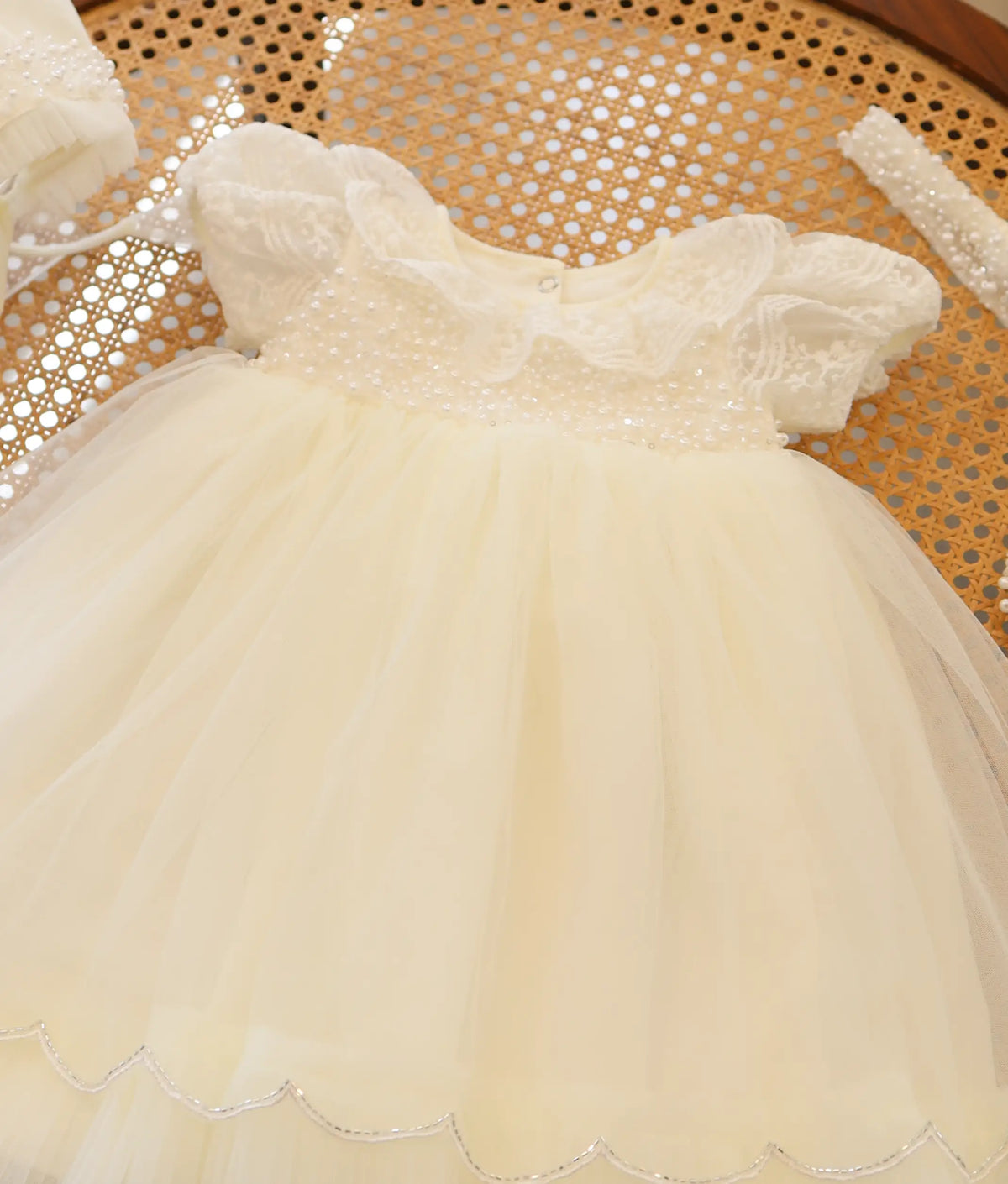Close-up view of off-white christening frock showing lace collar and handworked pearl yoke.