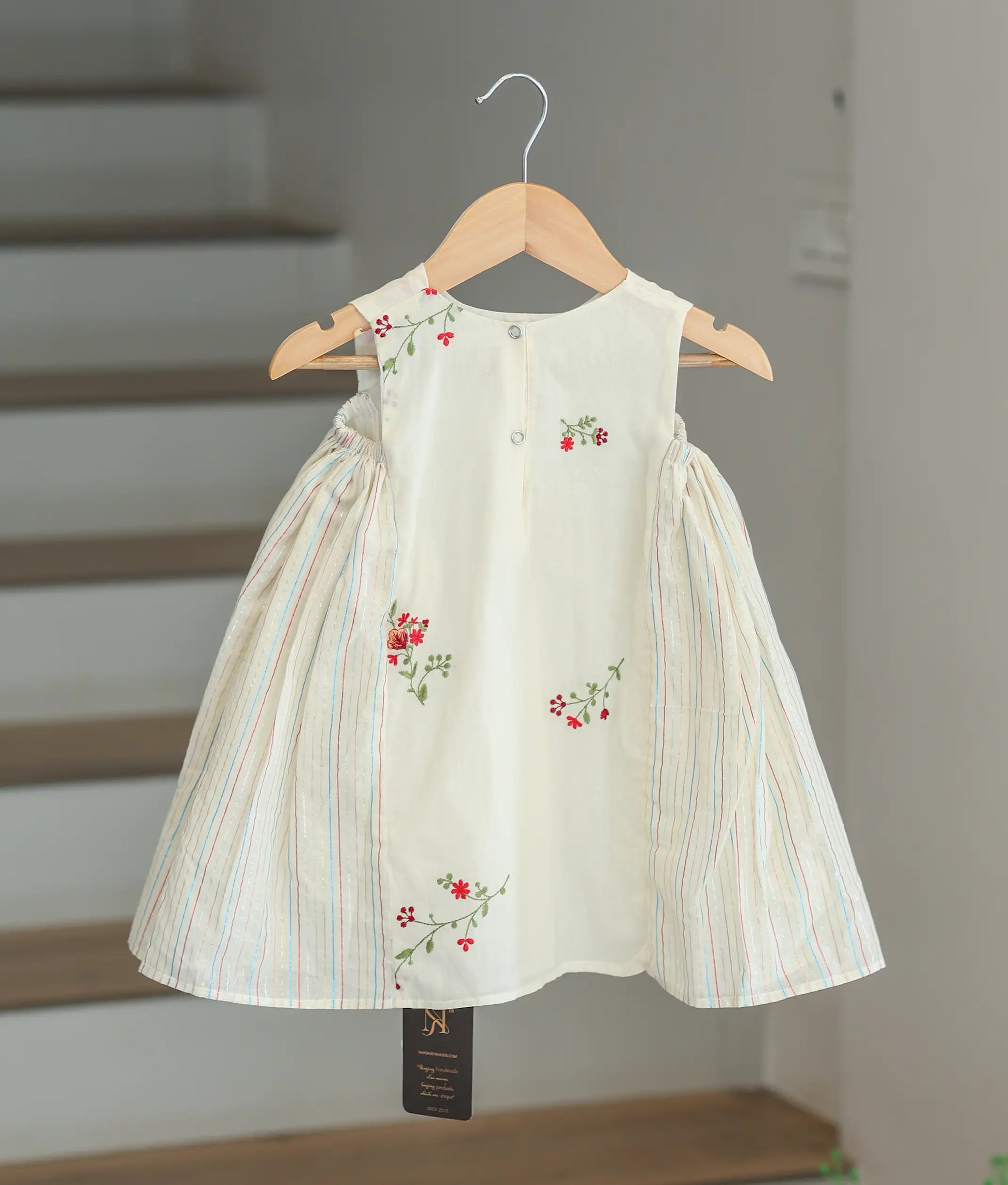 Back view of the off-white cotton printed frock showing the round neck and press button closure.
