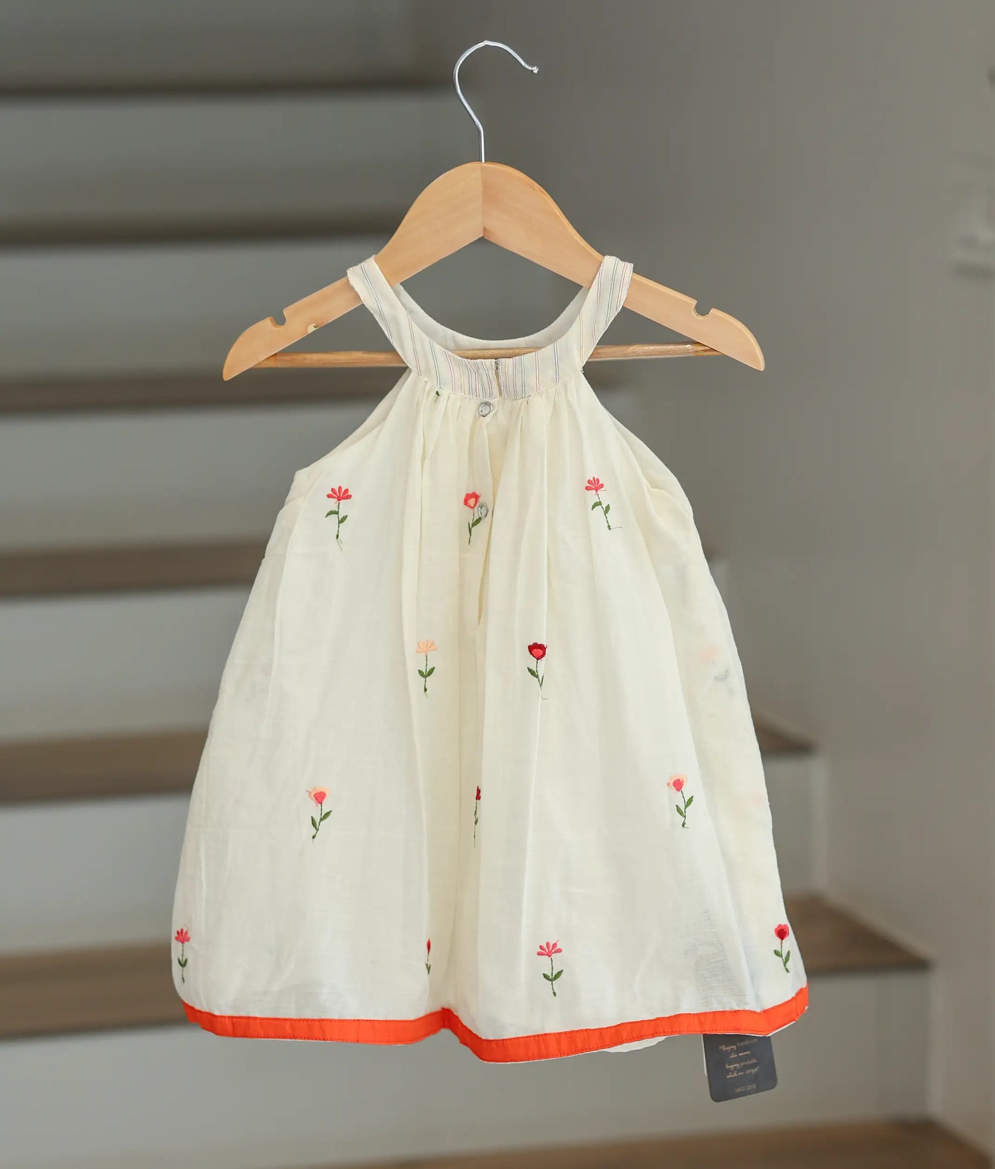 Back view of the off-white cotton floral frock showing the halter back and press button closure.