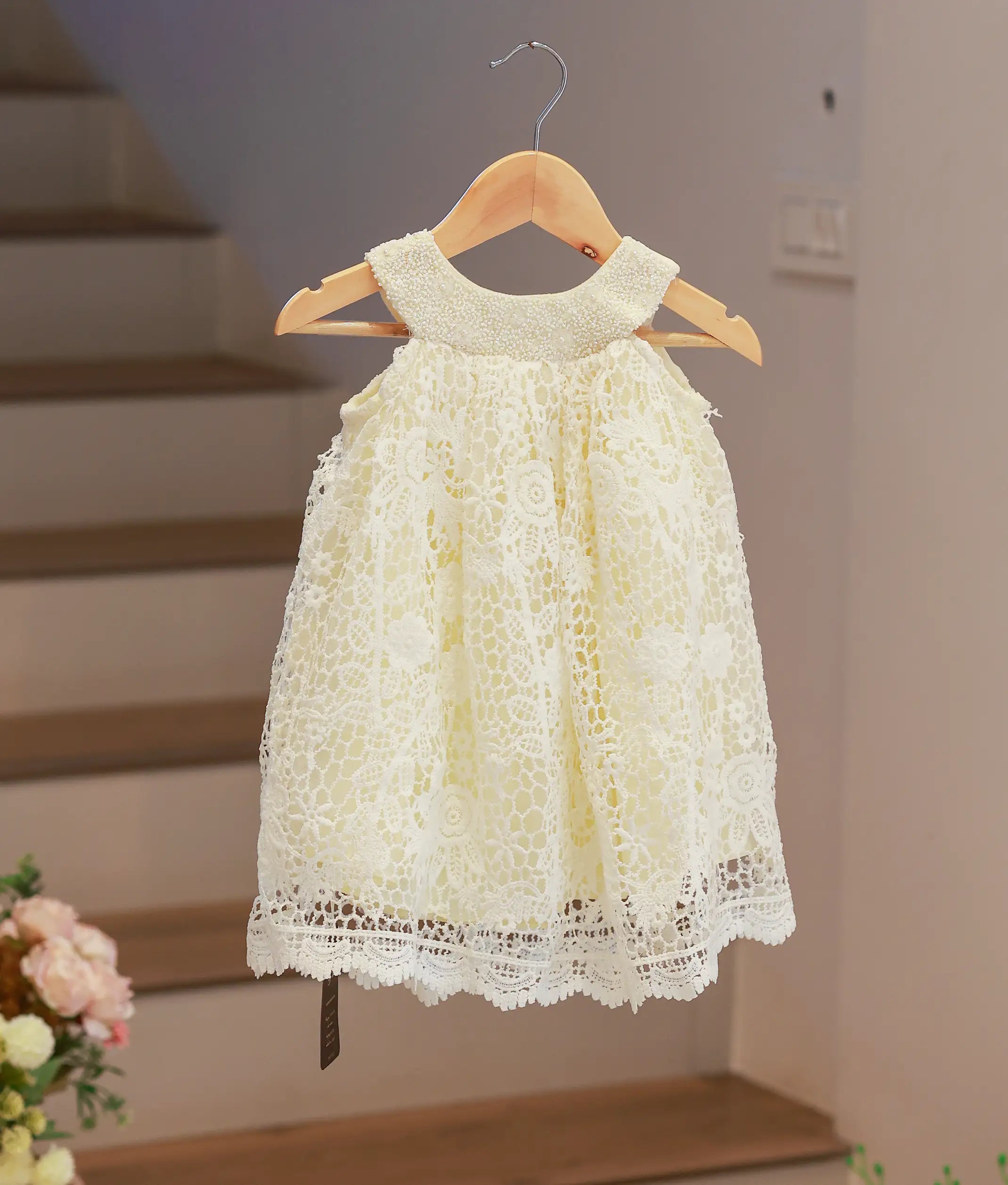 Front view of an off-white baby girl baptism frock featuring a classic A-line silhouette and a delicate crochet pattern.