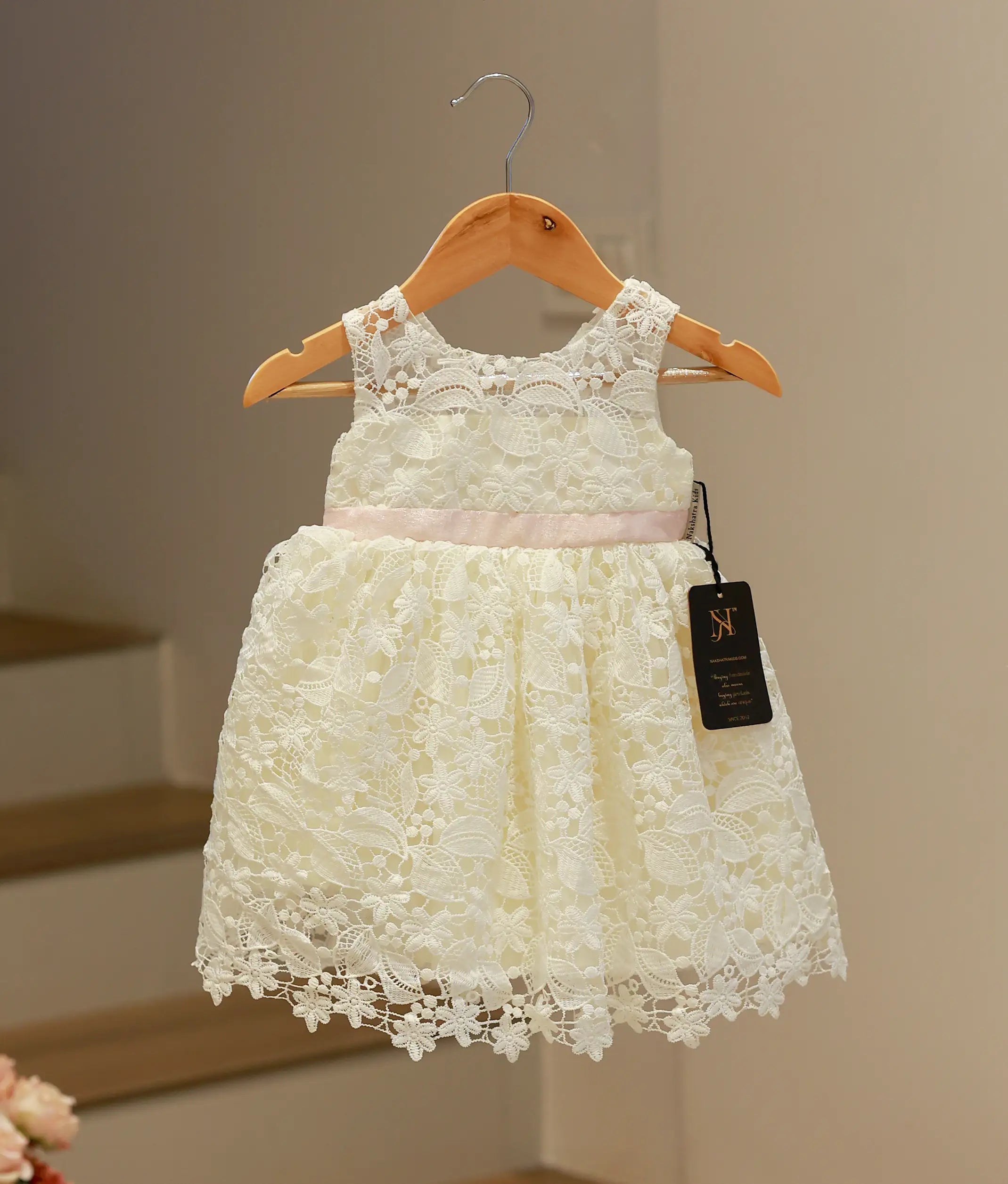 Front view of an elegant off-white baptism frock for baby girls featuring a classic crochet pattern and a soft flared skirt