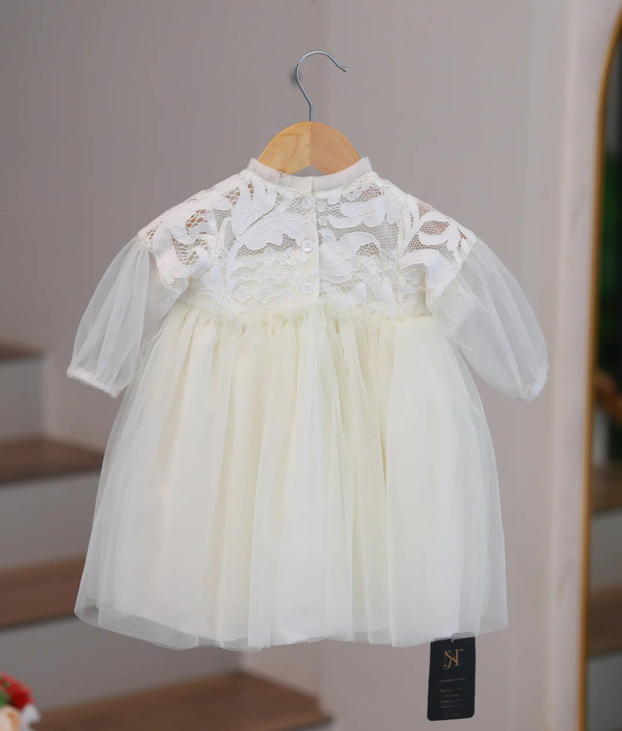 Back view of the off-white baptism frock highlighting the button closures and sheer sleeve detail.
