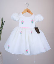 Front view of an off-white crush organza flower theme dress for baby girls featuring puffed sleeves and scattered floral embroidery on the yoke and skirt