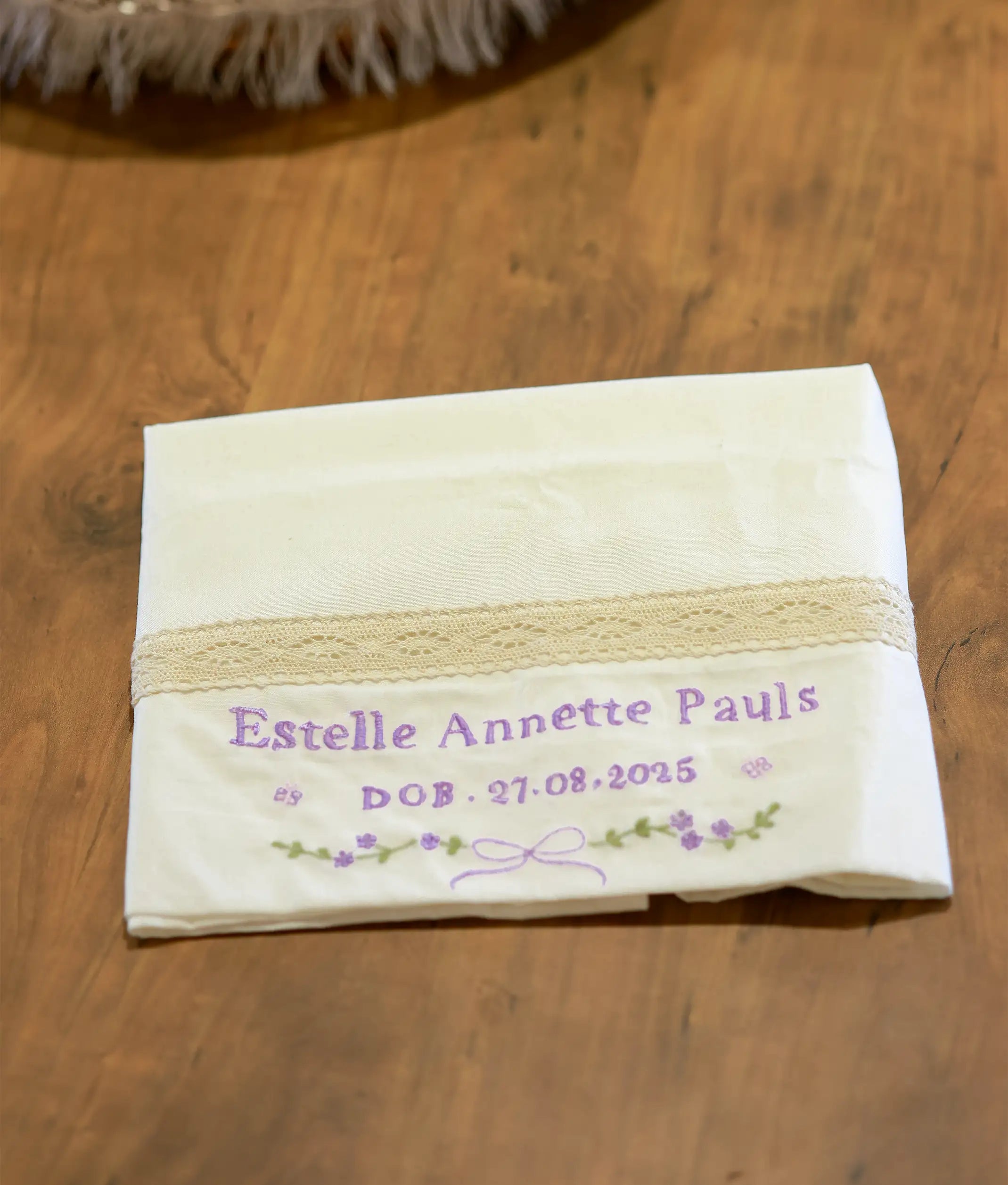 An off-white baptism towel for baby featuring delicate floral embroidery and lace trim for christening ceremonies