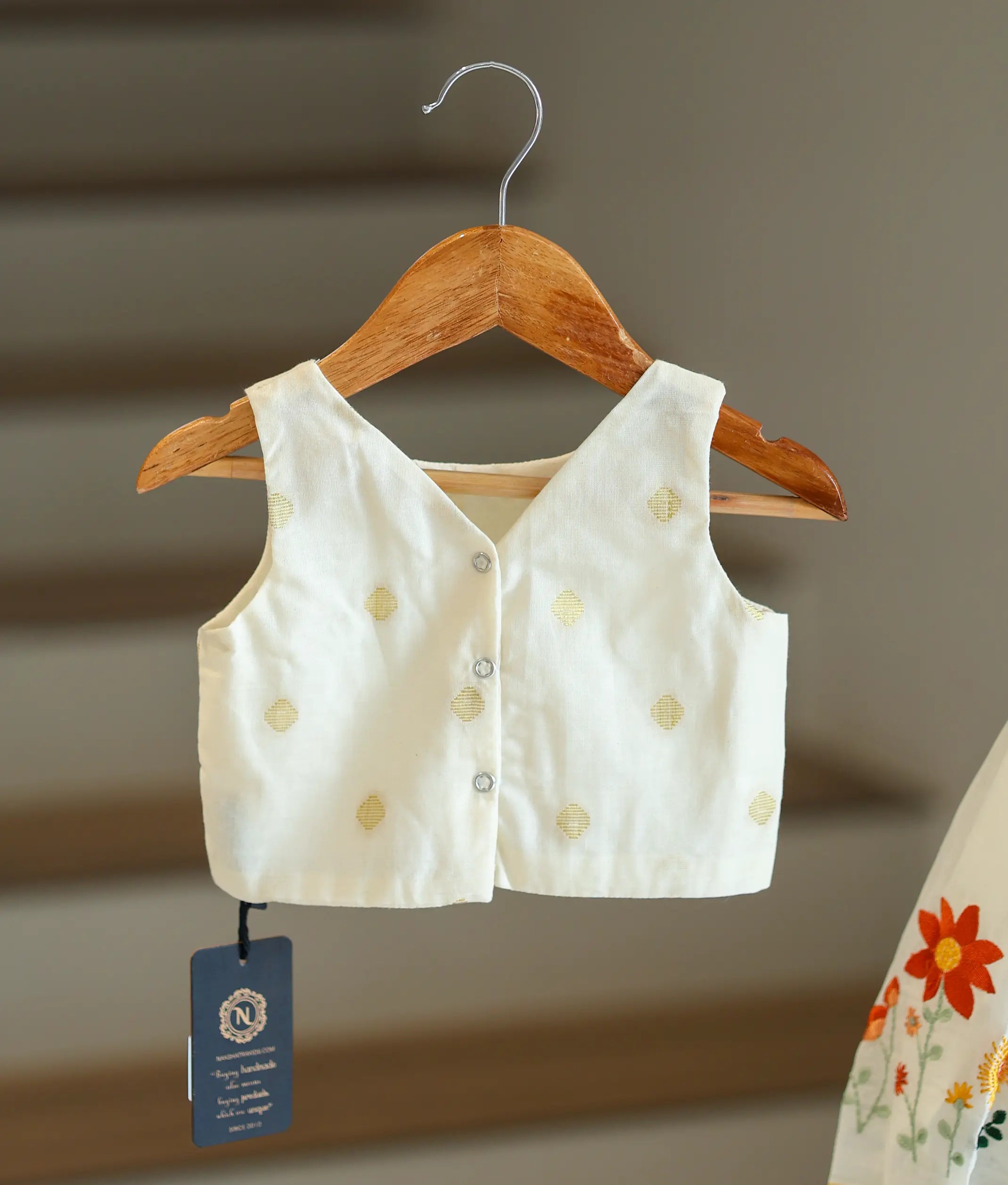 Back view of the off-white top showing the embroidery and secure button closures.