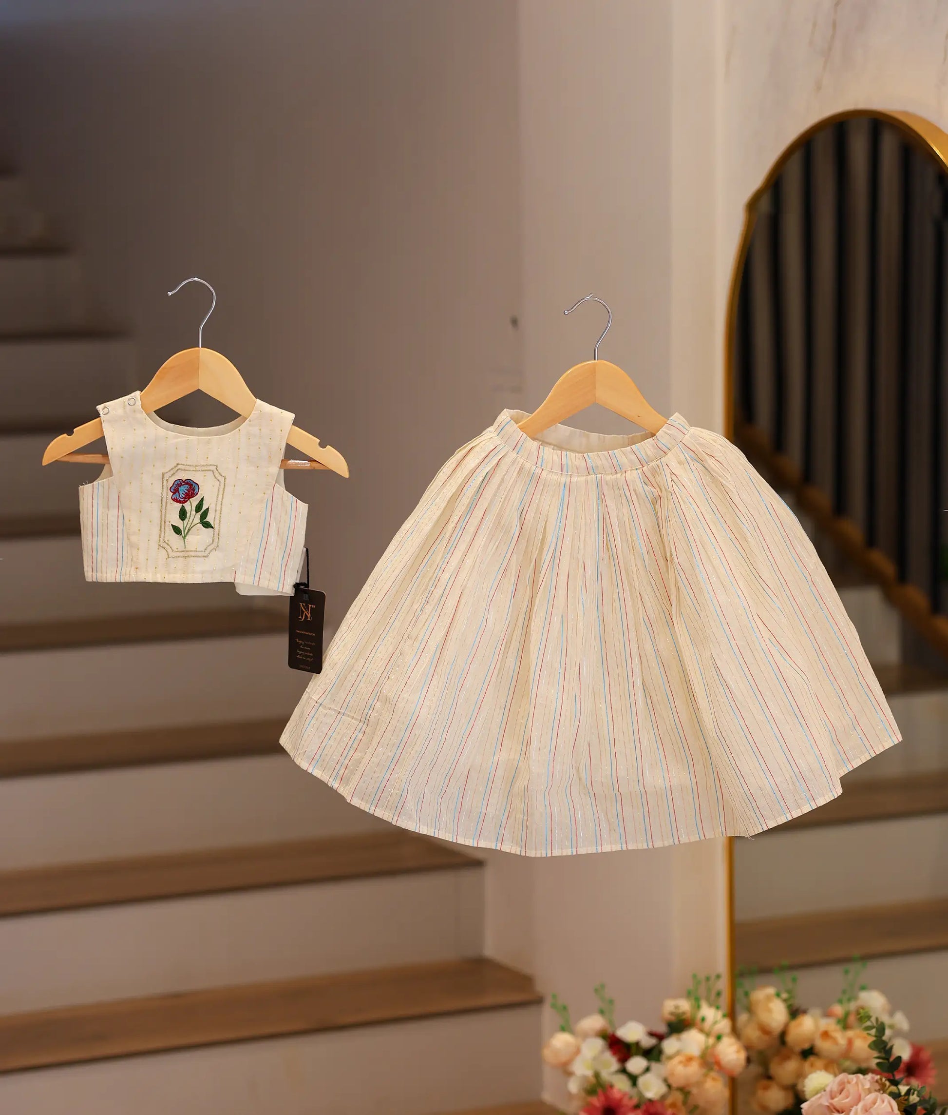 Front view of an off-white cotton skirt and top set for girls with colorful floral hand-embroidery