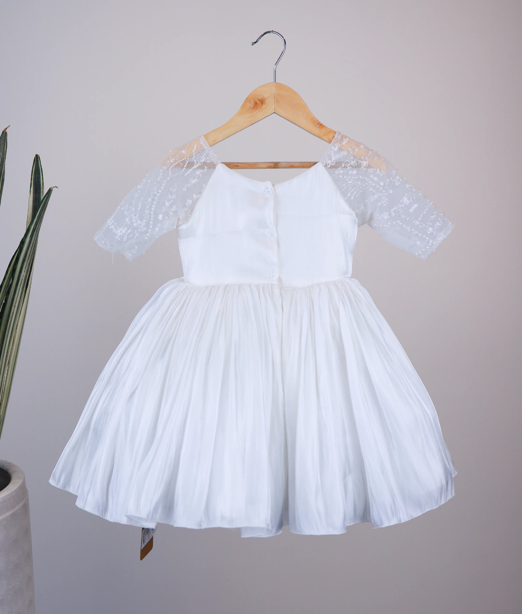 Back view of off-white lacer organza flower girl dress showing the round neckline and show button closure