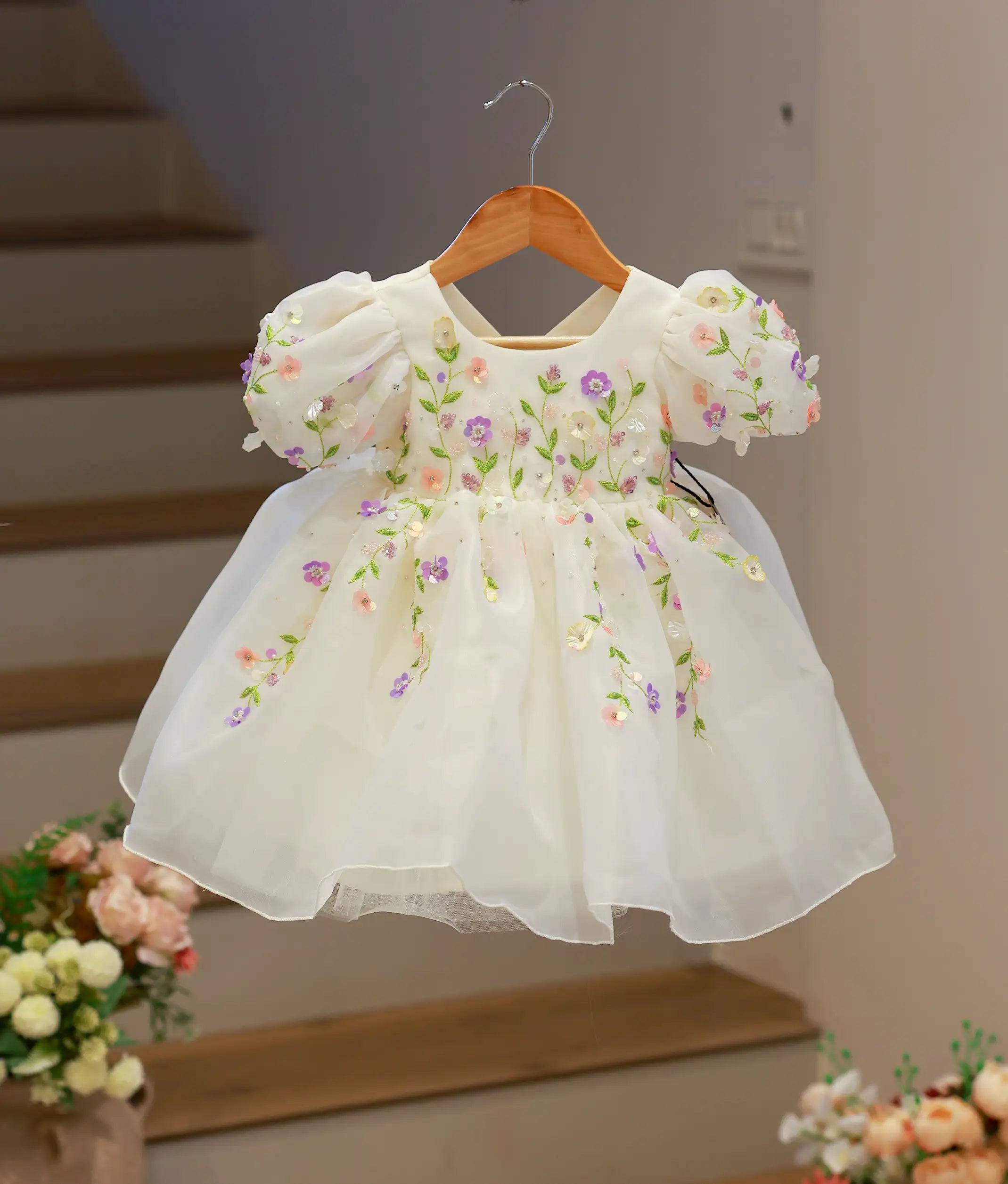 Full front view of an off-white organza birthday frock with colorful floral embroidery and puffed sleeves