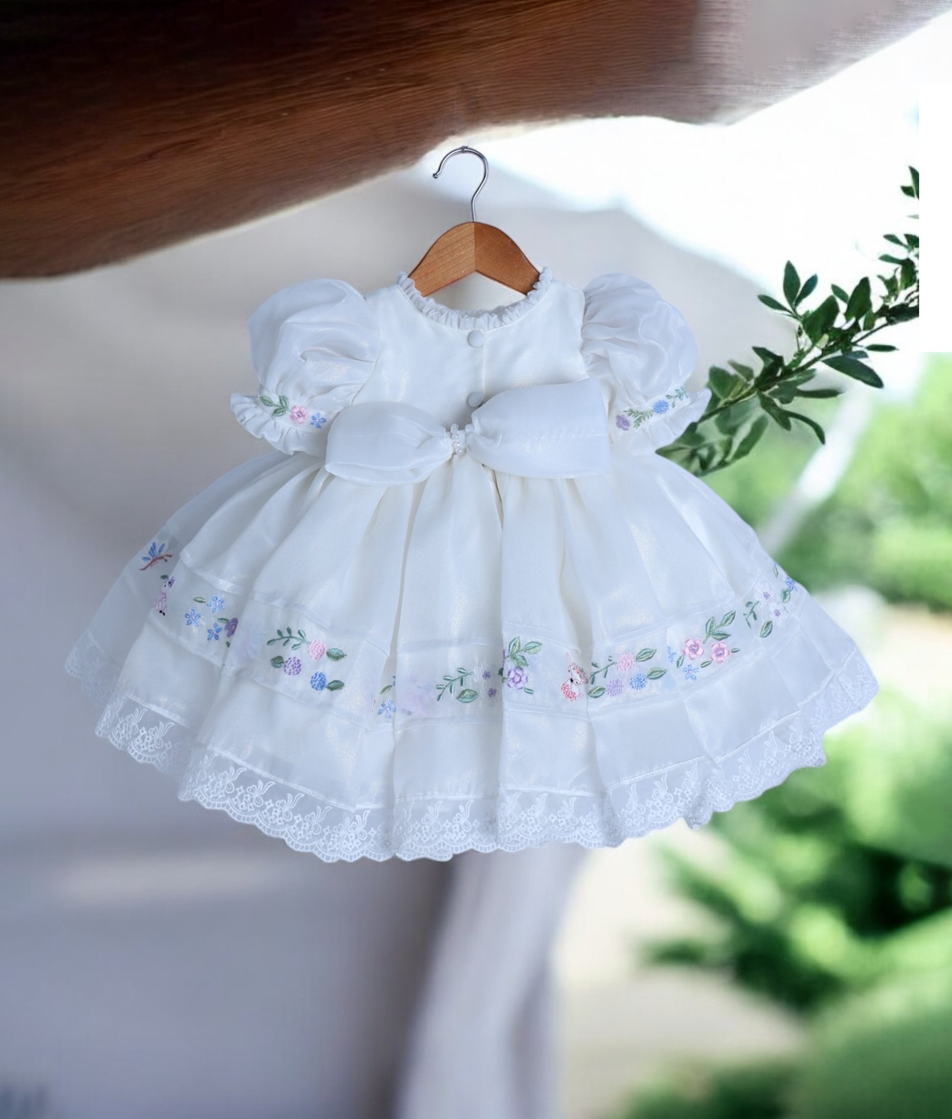 Back view of the off-white frock showing the elegant back bow, puff sleeves, and round neck with show button