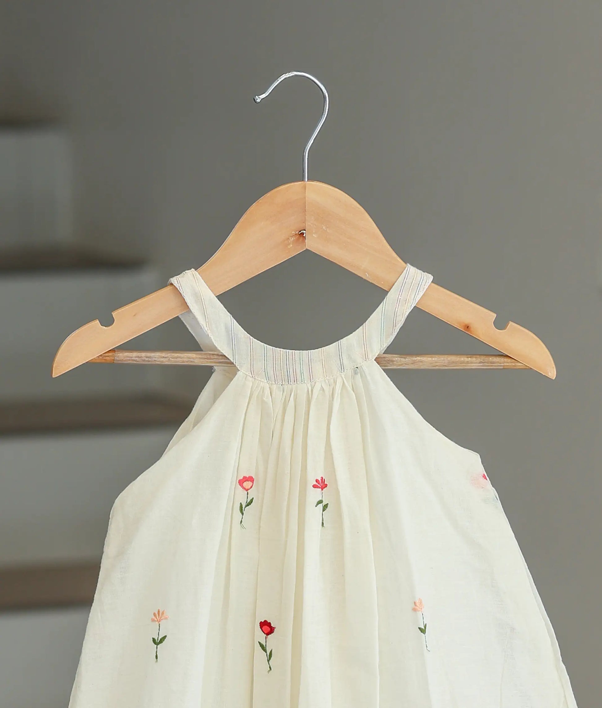 Close-up of the vertical stripes on the halter neck and the floral print on the off-white cotton fabric.