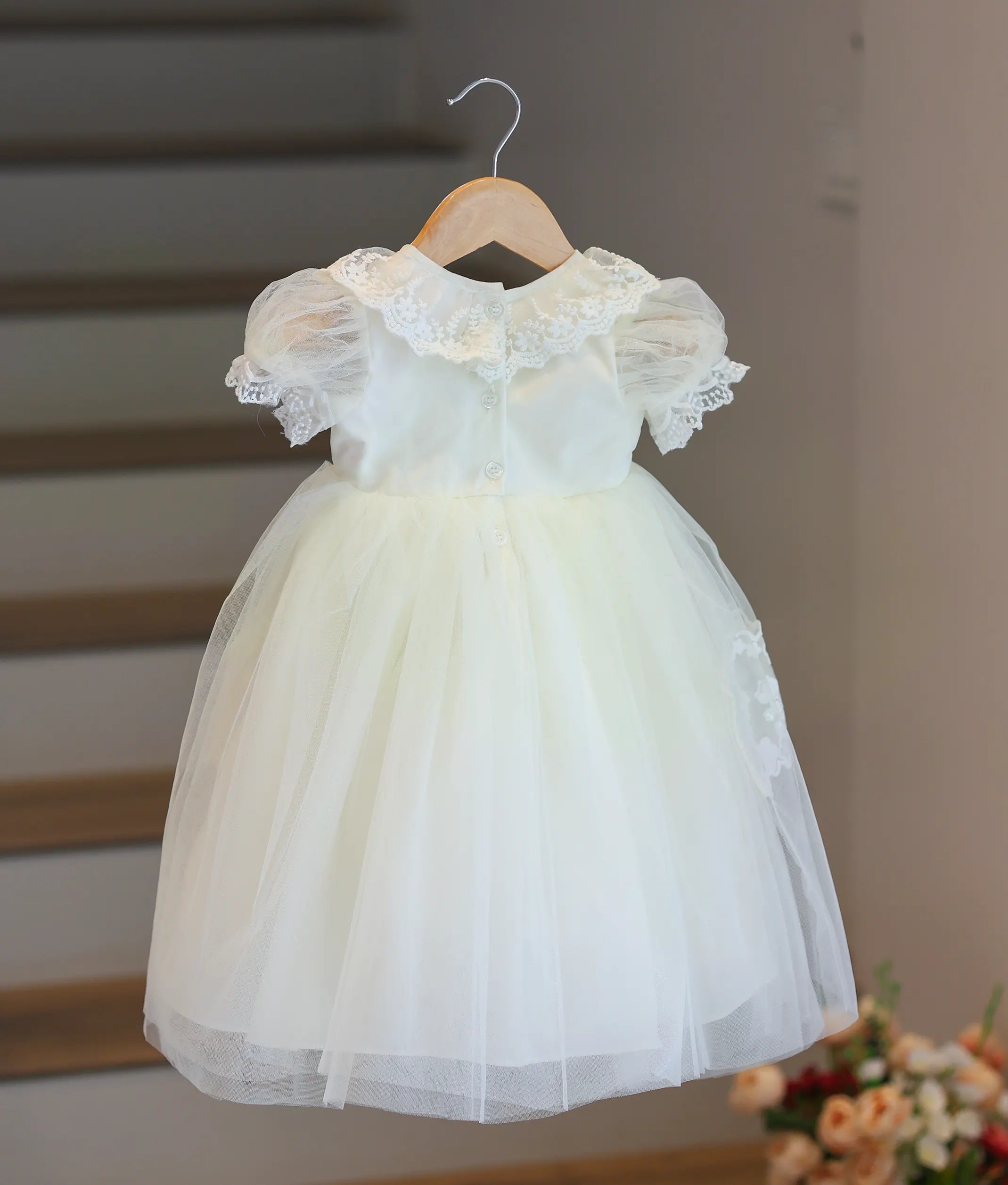 Back view of off-white girl's baptism gown with lace collar, puff sleeves and layered soft tulle skirt