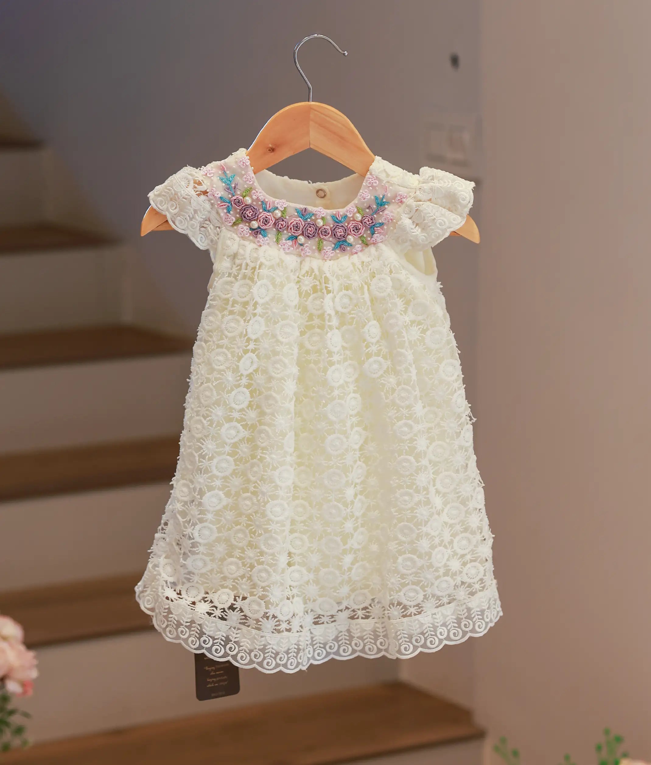 Front view of an off-white baptism frock featuring an intricate hand-worked crochet bodice and a soft flowing skirt.