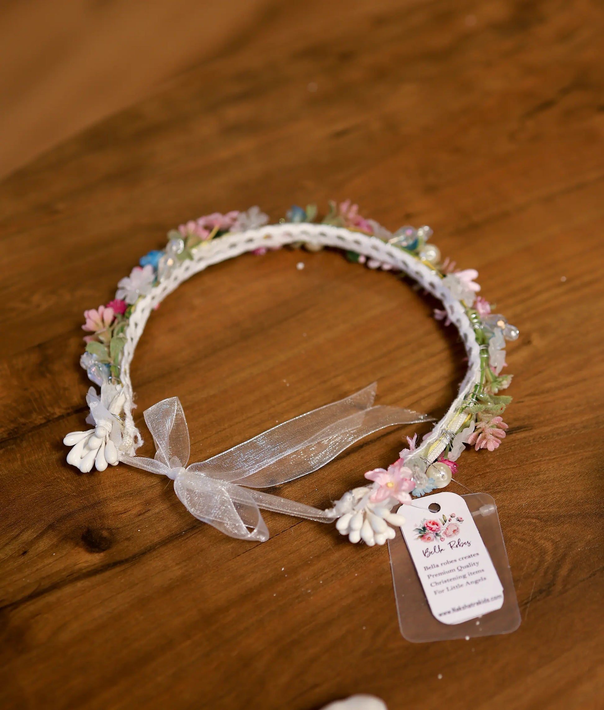 Delicate baptism floral crown headband with soft pink blossoms, pastel beads, and a sheer white ribbon bow.