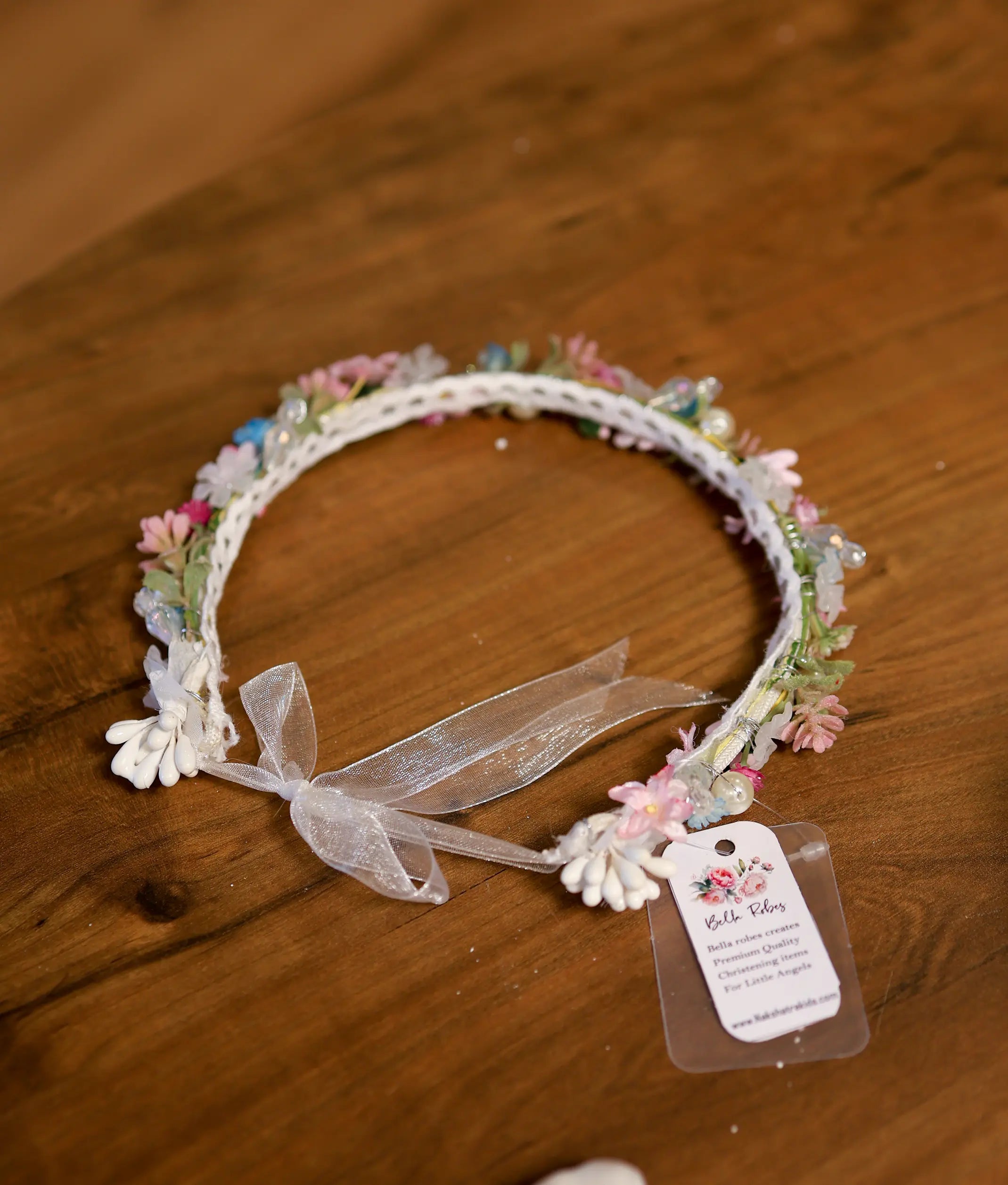 Delicate baptism floral crown headband with soft pink blossoms, pastel beads, and a sheer white ribbon bow.