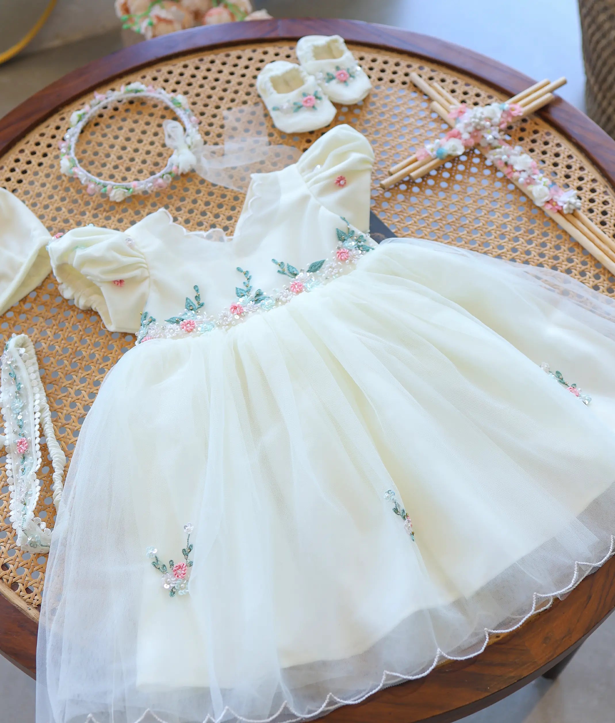 Frock view of off-white tulle net baby girl baptism dress with delicate pink and green flower handwork embroidery on the waistline.
