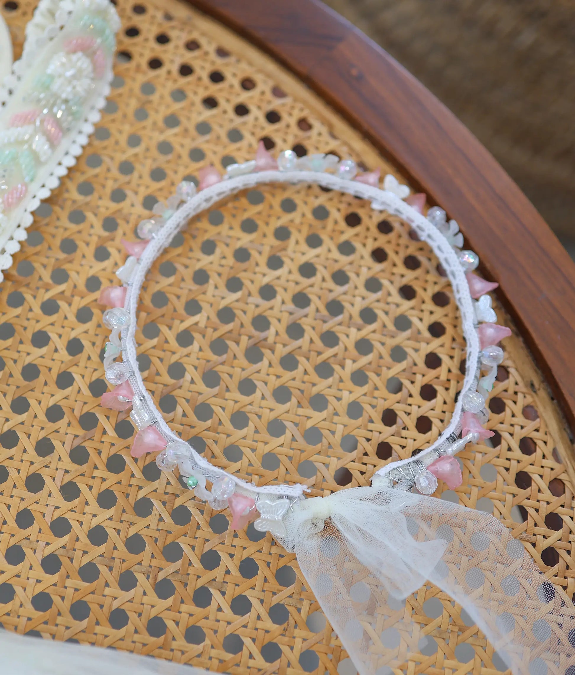 Delicate baptism floral crown featuring soft pink and white flower details, clear beads, and net bow.
