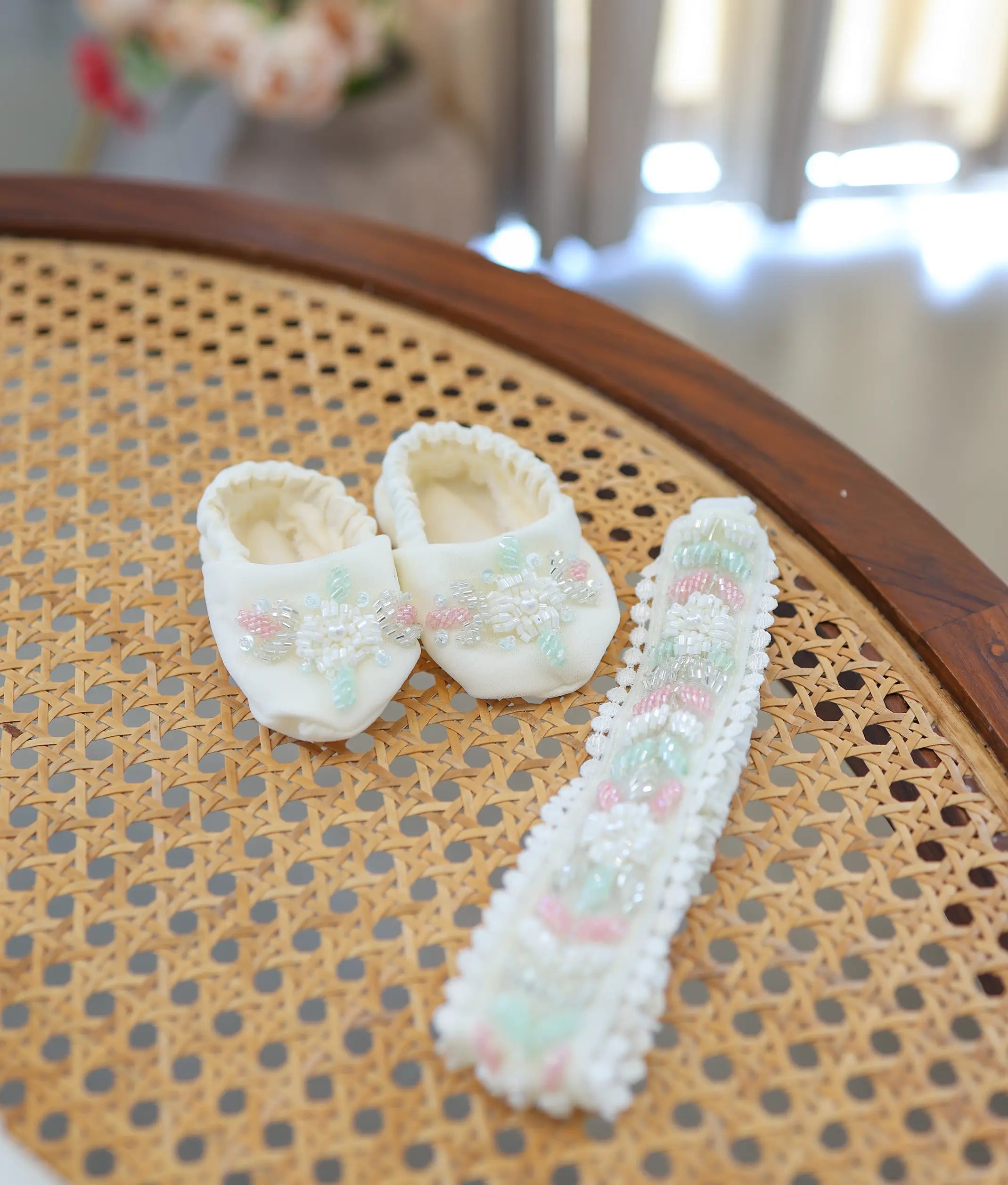 Matching off-white baby booties and elastic lace headband featuring pink and green handwork embroidery.