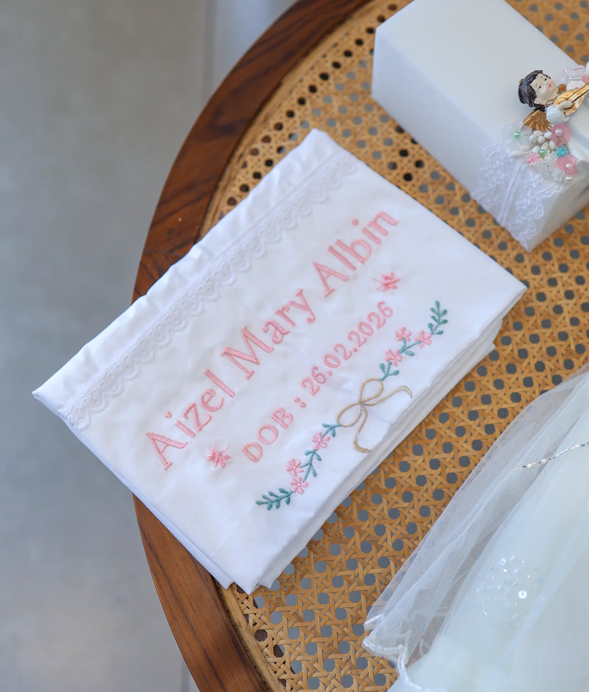 Personalized white baptism towel with pink embroidered name, date of birth, and floral vine border.