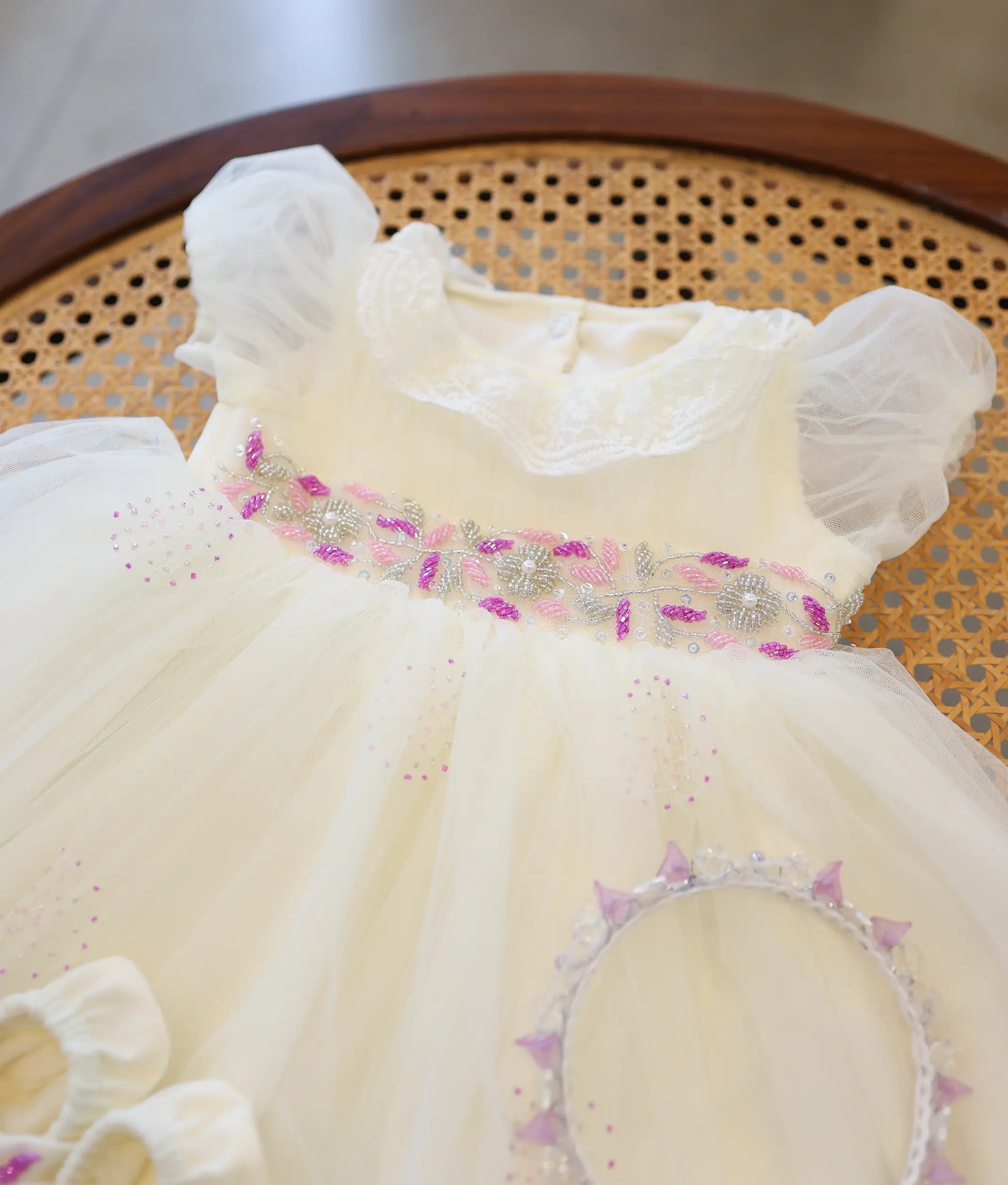 Close-up of off-white baby girl baptism frock top showing pink and silver handwork bead embroidery at the waist and lace collar.