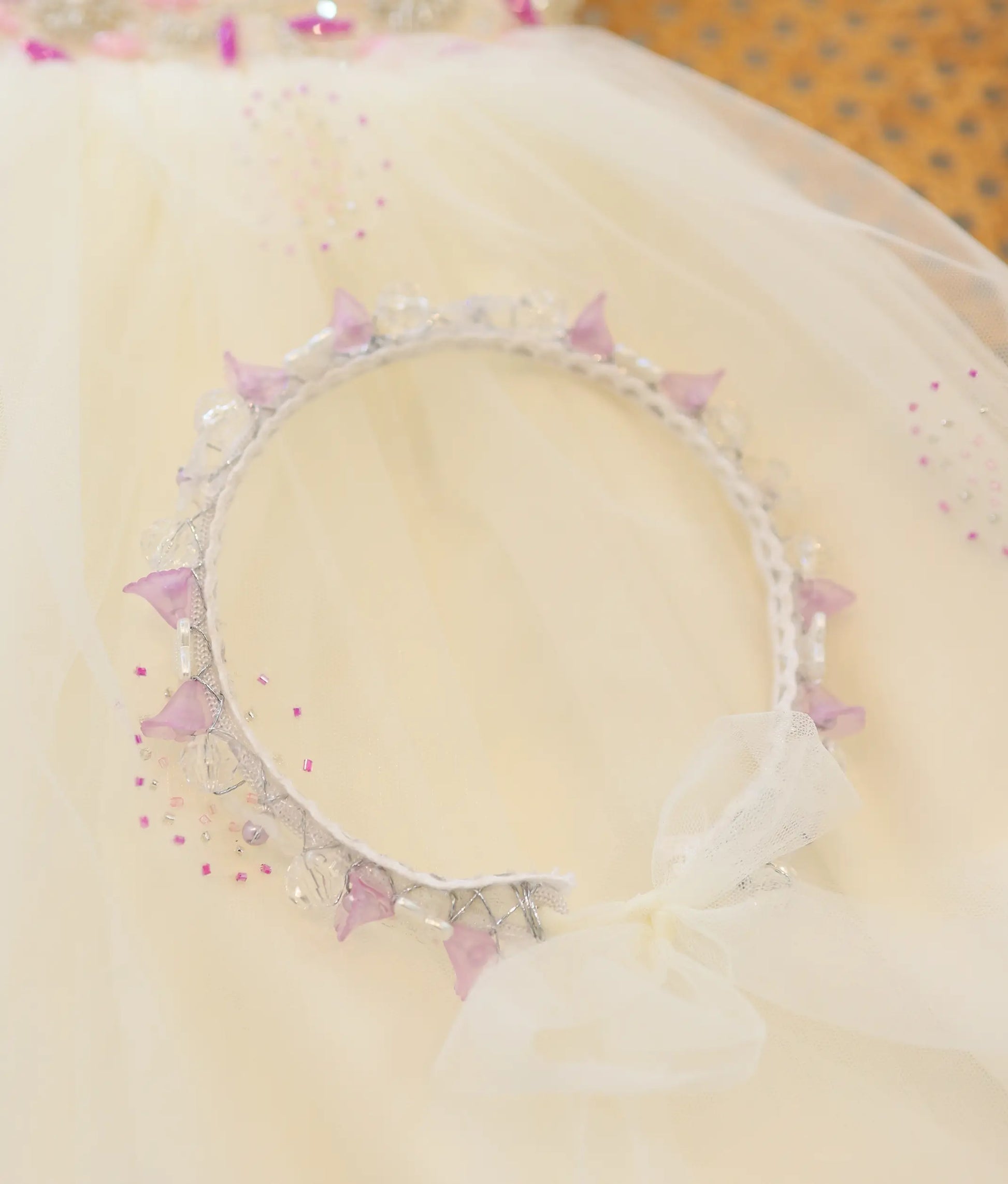 Off-white baby girl baptism headband with purple flower accents, beads, and net bow detail.Off-white baby girl baptism headband with purple flower accents, beads, and net bow detail.