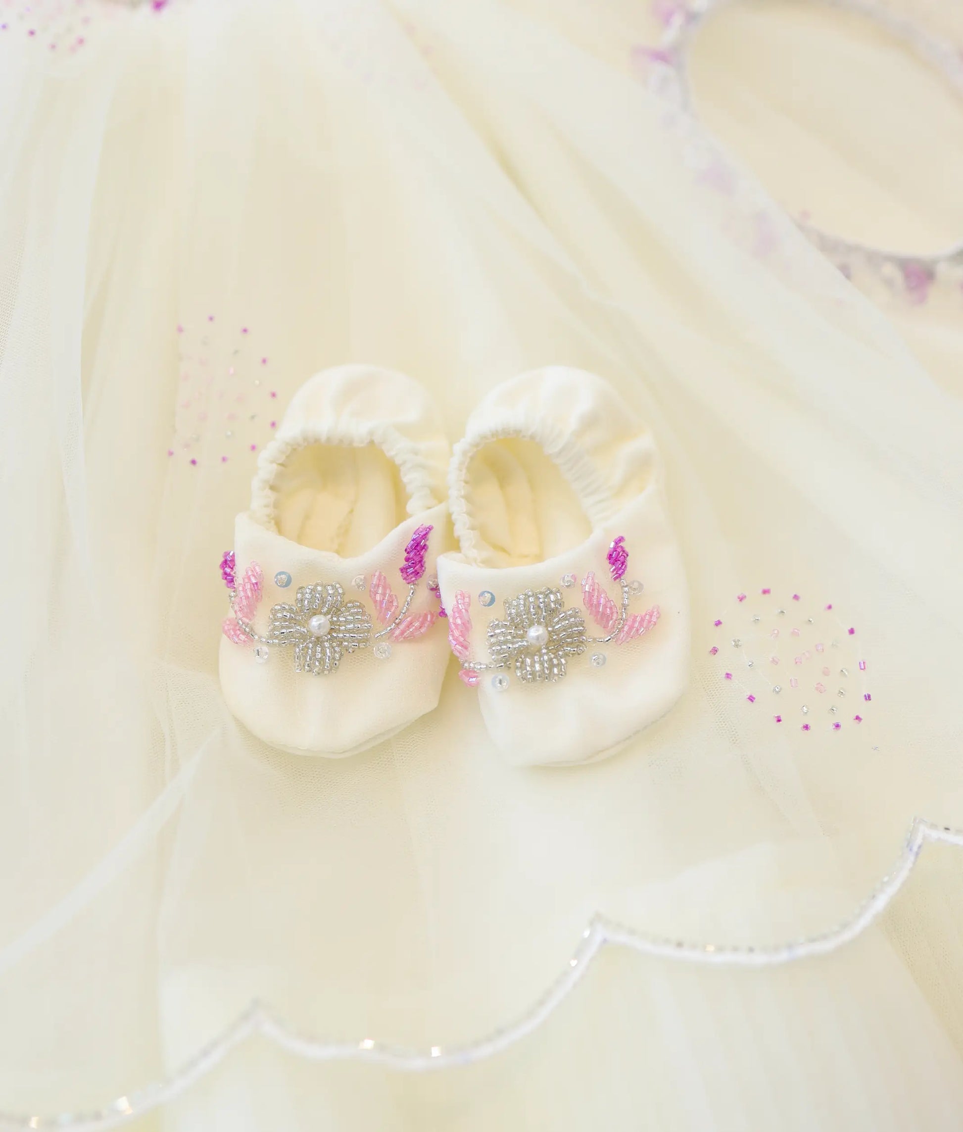 Off-white soft baptism booties for baby girl decorated with silver bead flowers and pink leaves.Off-white soft baptism booties for baby girl decorated with silver bead flowers and pink leaves.