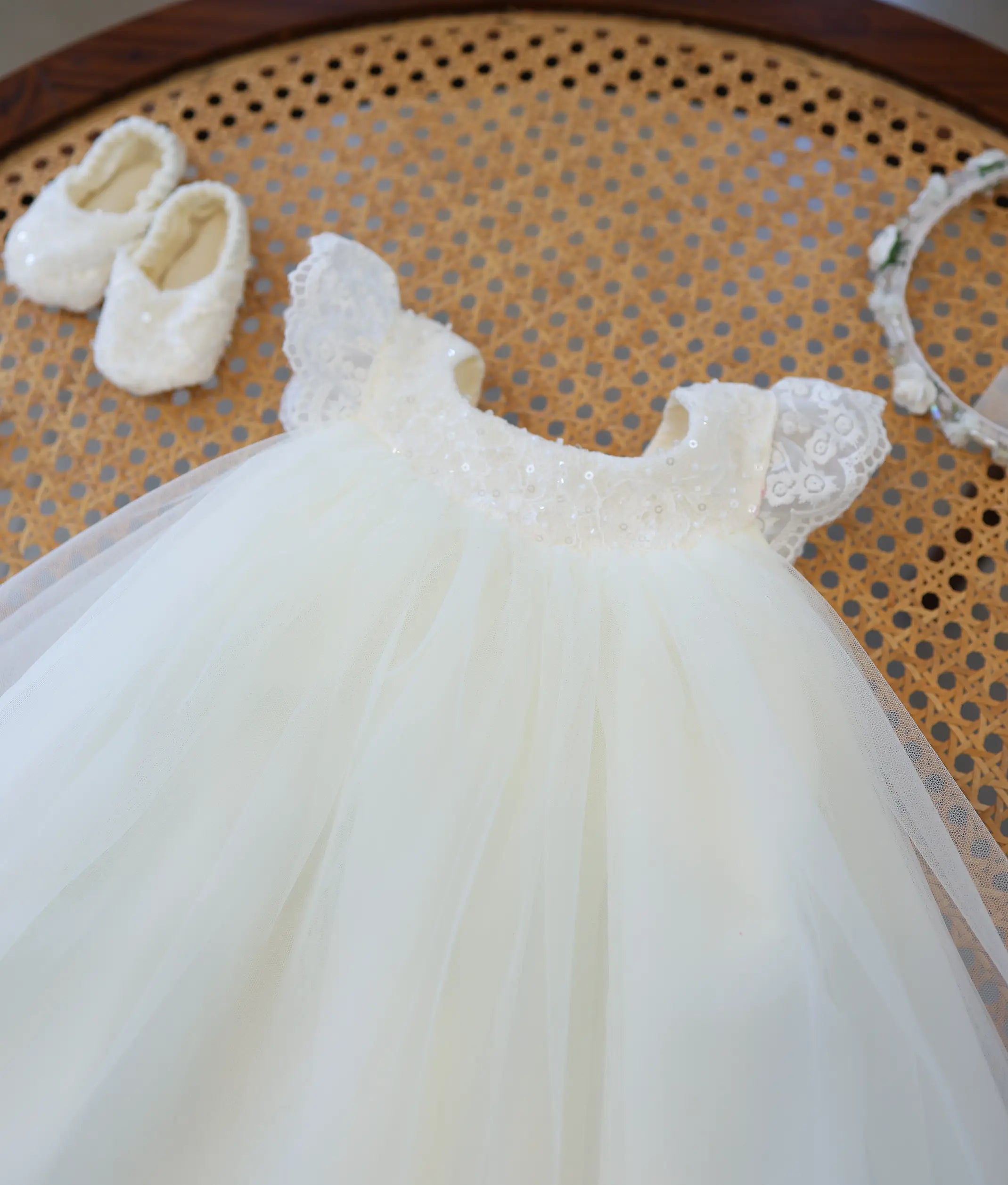 Close-up of off-white baby girl baptism frock top featuring sequin handwork embroidery on the round neckline and lace flutter sleeves.