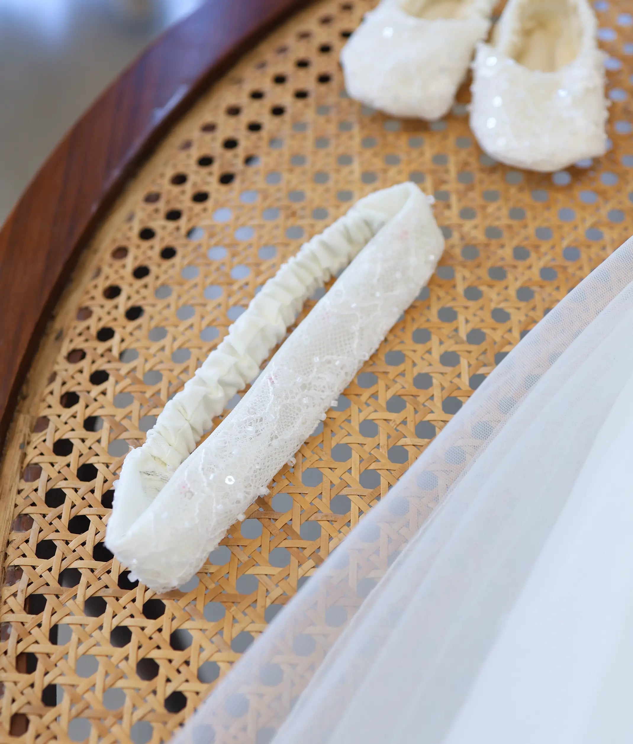 Soft off-white elastic baptism headband for baby girl with detailed lace overlay and subtle sequin accents.