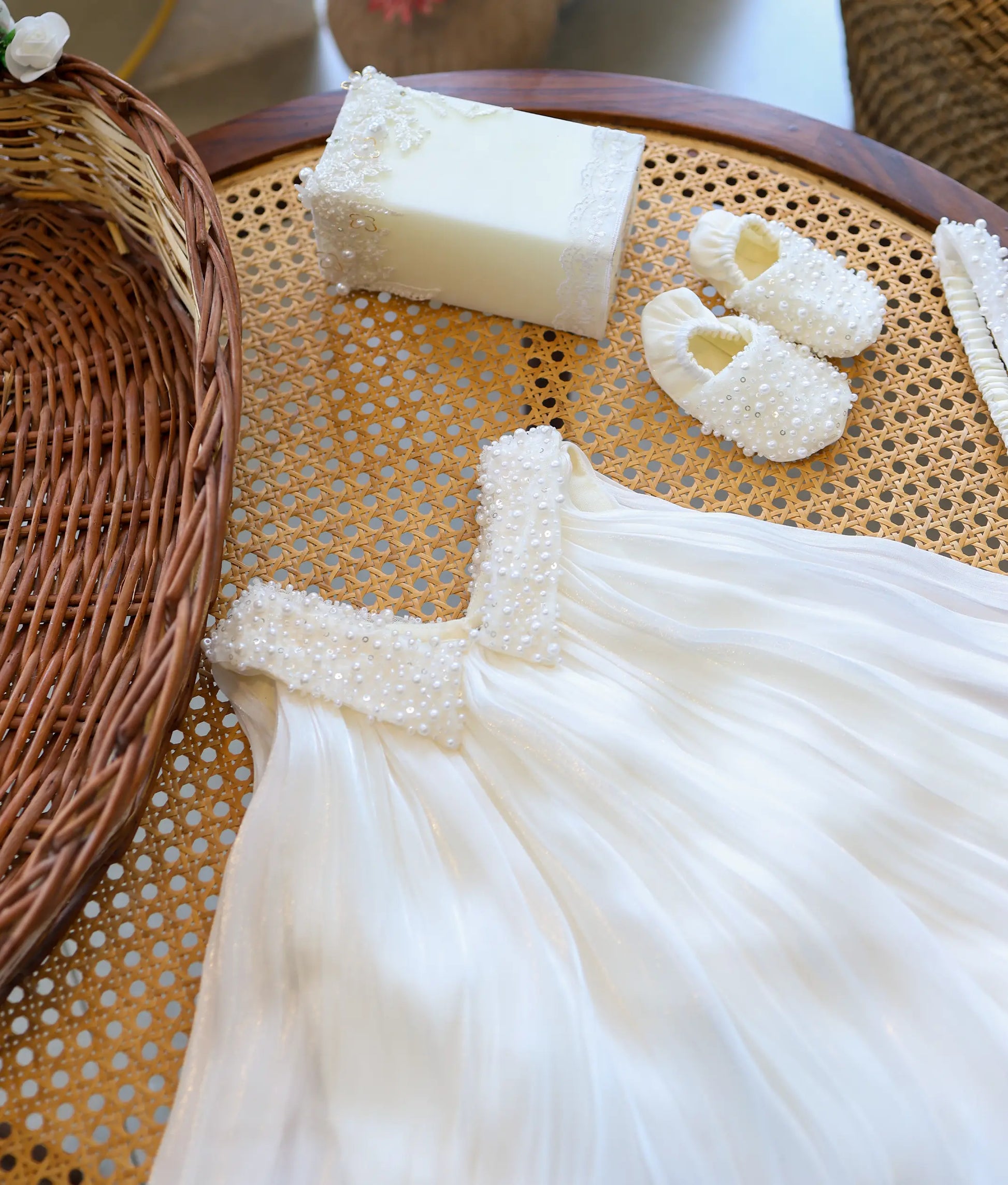 Close-up of off-white baby girl baptism frock highlighting the V-neckline with intricate pearl-beaded collar and pleated organza skirt.
