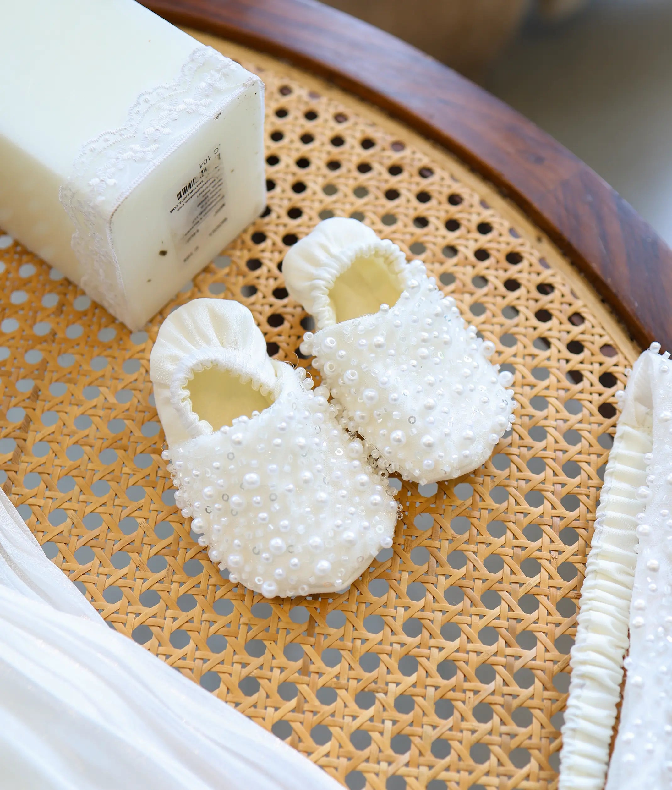 Pair of soft off-white baby girl baptism booties heavily embellished with pearls and sequins.