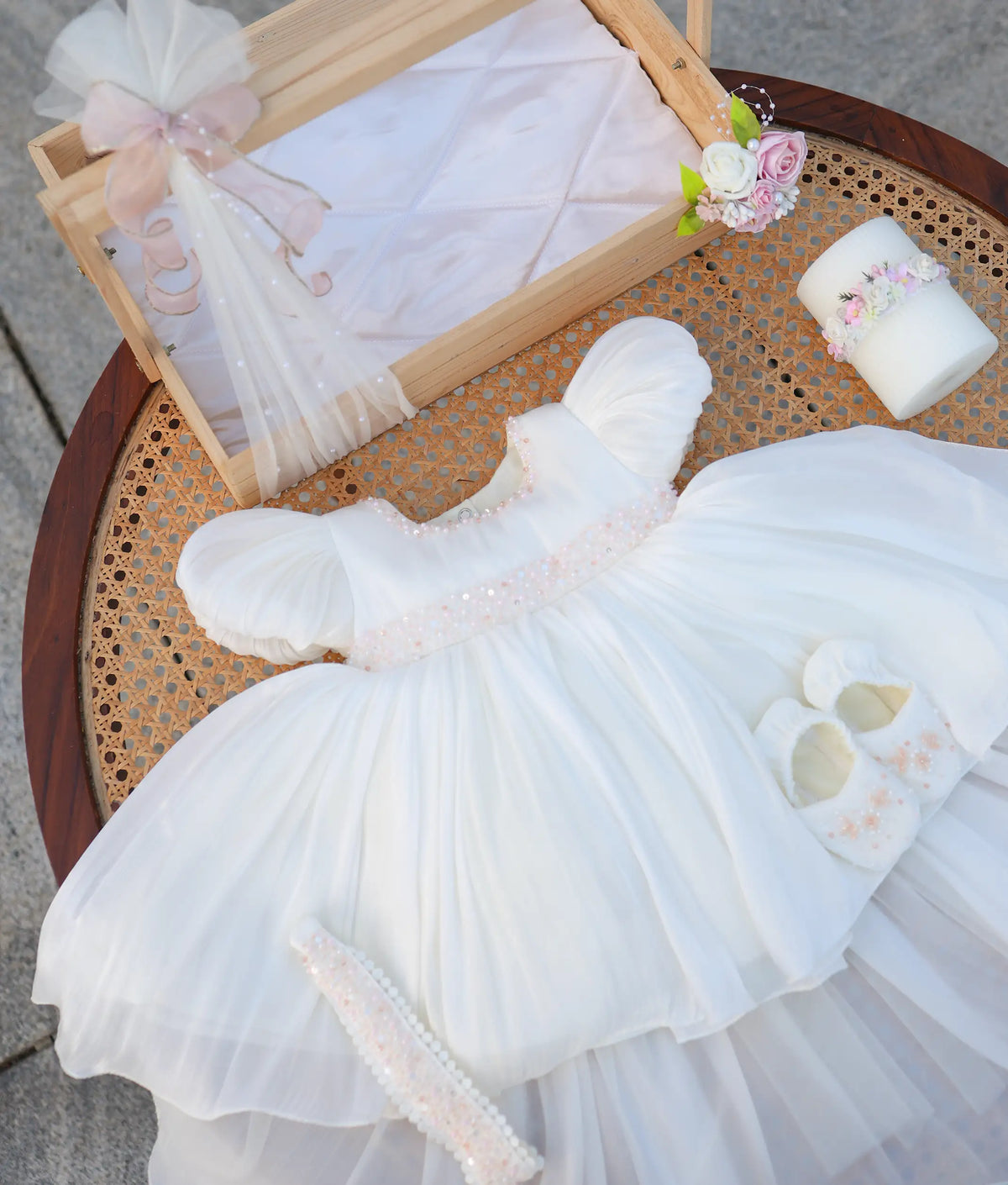 Complete off-white handwork baptism set for baby girl featuring puffed sleeve frock, embellished headband, matching booties, decorated candle, and wooden basket.