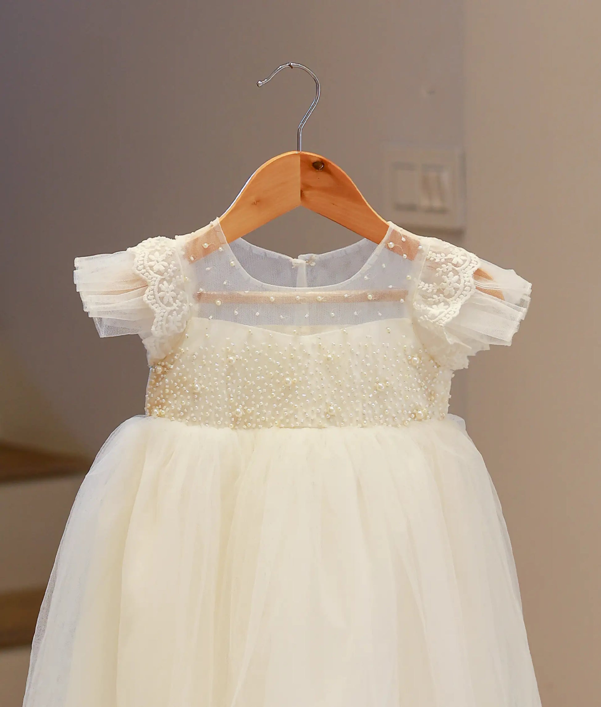 Detailed close-up of the off-white baptism frock showing the intricate handworked floral patterns and delicate beadwork on the yoke.