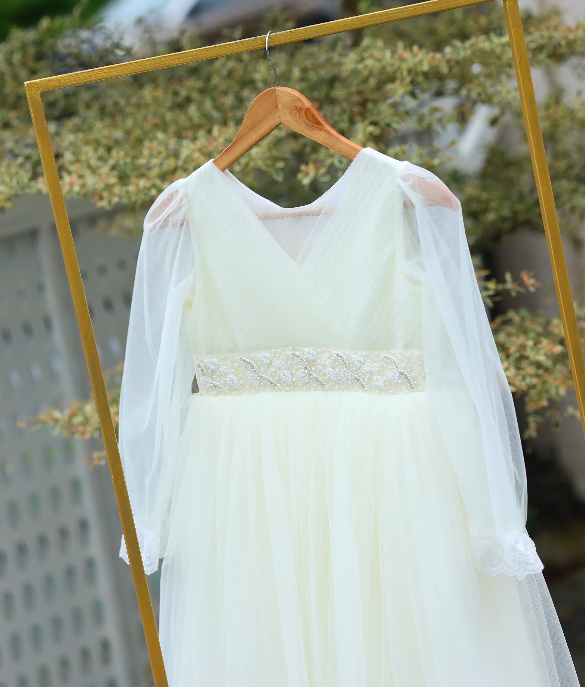 Close-up view of the dress showing the hand-worked pearl belt and pleated tulle bodice.